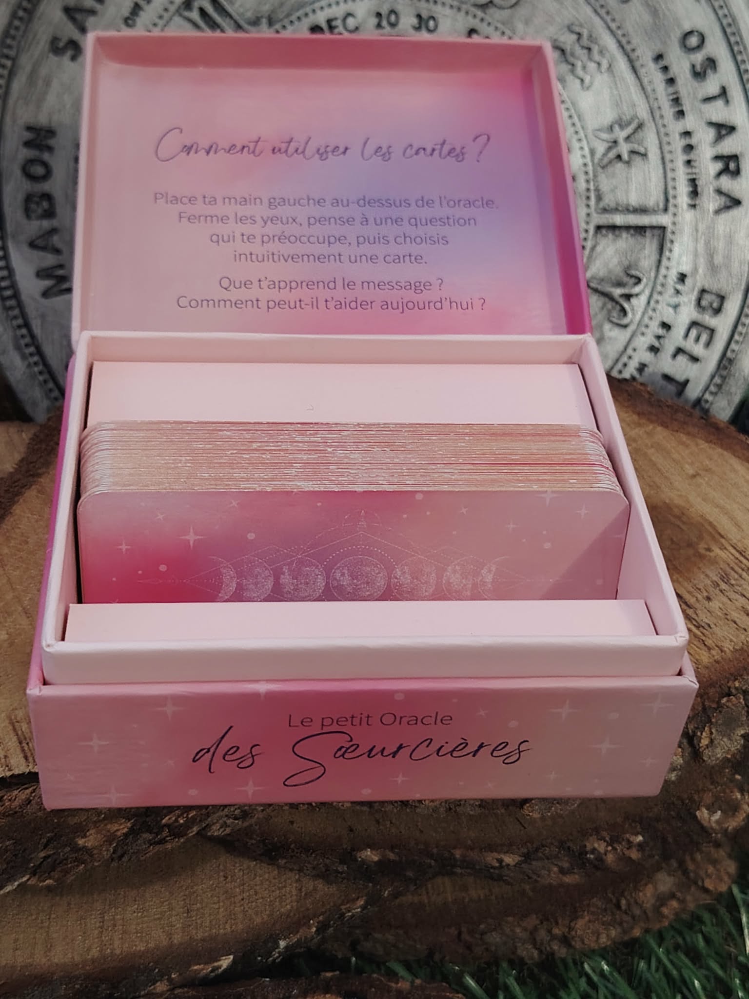 Boîte ouverte du Petit Oracle des Sœurcières (L’Atelier des Sœurcières) : cartes rose/violet rangées dans le coffret, décor ésotérique avec fond mandala gris et ambiance witchy