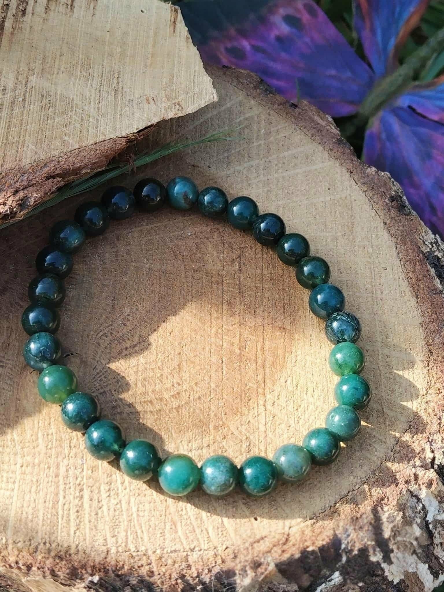 Bracelet Agate Mousse 6 mm bleu-vert sur tranche de bois avec tissu violet en fond, apaisement et douceur du cœur