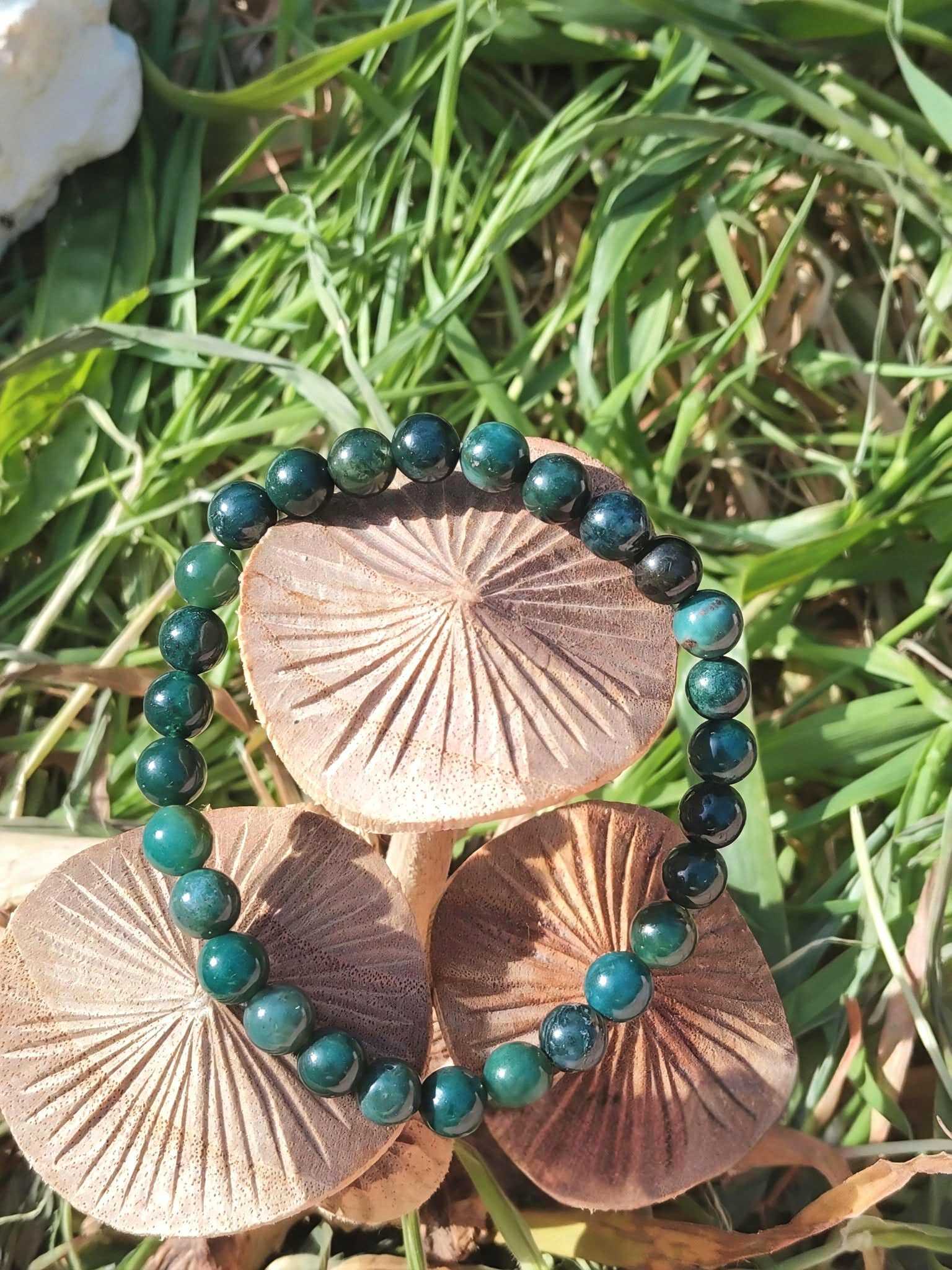Bracelet Agate Mousse 6 mm bleu-vert posé sur des champignons dans l’herbe, calme émotionnel et lien au vivant