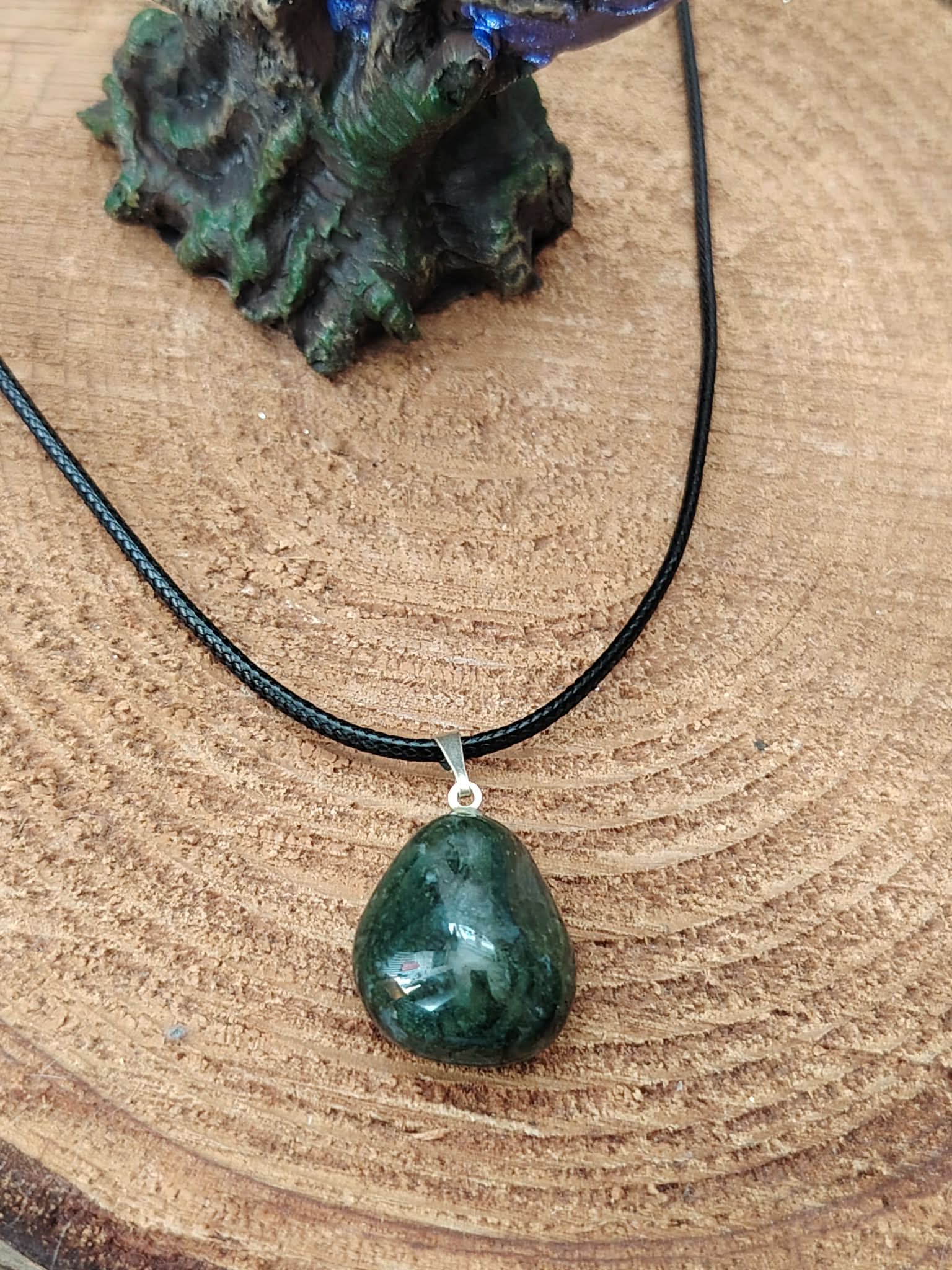 Pendentif agate mousse vert-bleuté sur cordon noir, photographié sur tranche de bois, équilibre émotionnel et présence apaisée