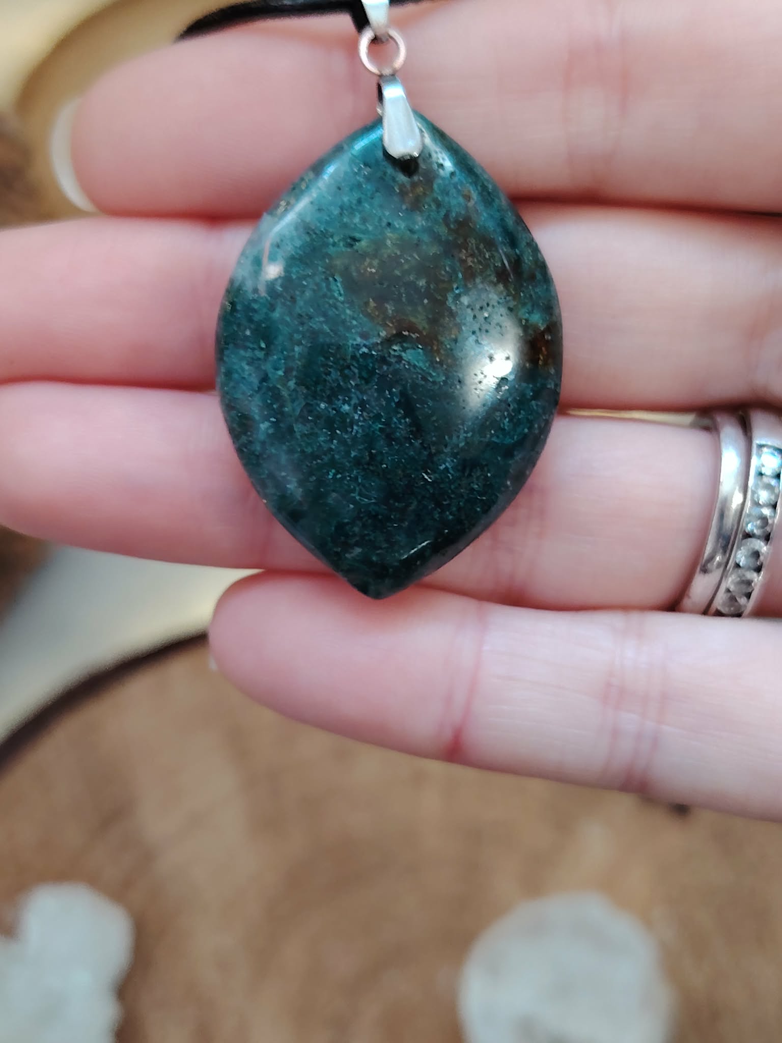 Pendentif agate mousse (goutte) sur cordon noir, gros plan en main ; pierre douce du chakra cœur, aide à relâcher le stress et à retrouver la sérénité.