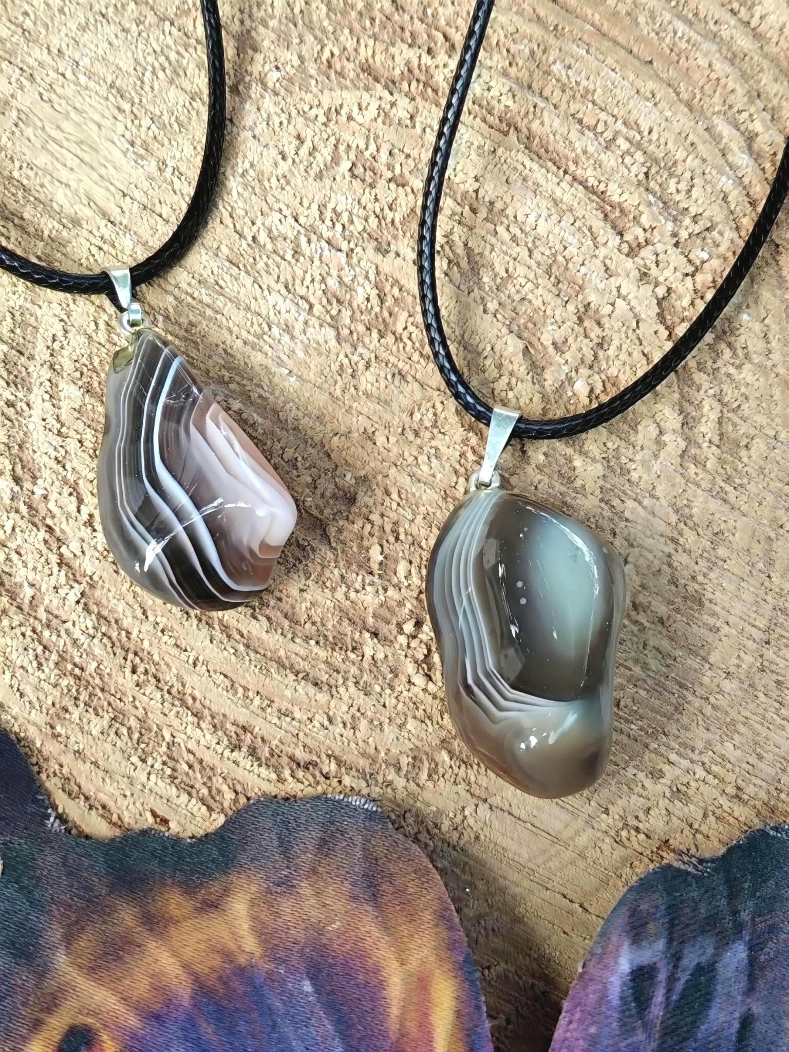 Pendentif agate du Botswana sur cordon noir, présenté sur tissu beige aux tons naturels pour douceur intérieure et stabilité émotionnelle