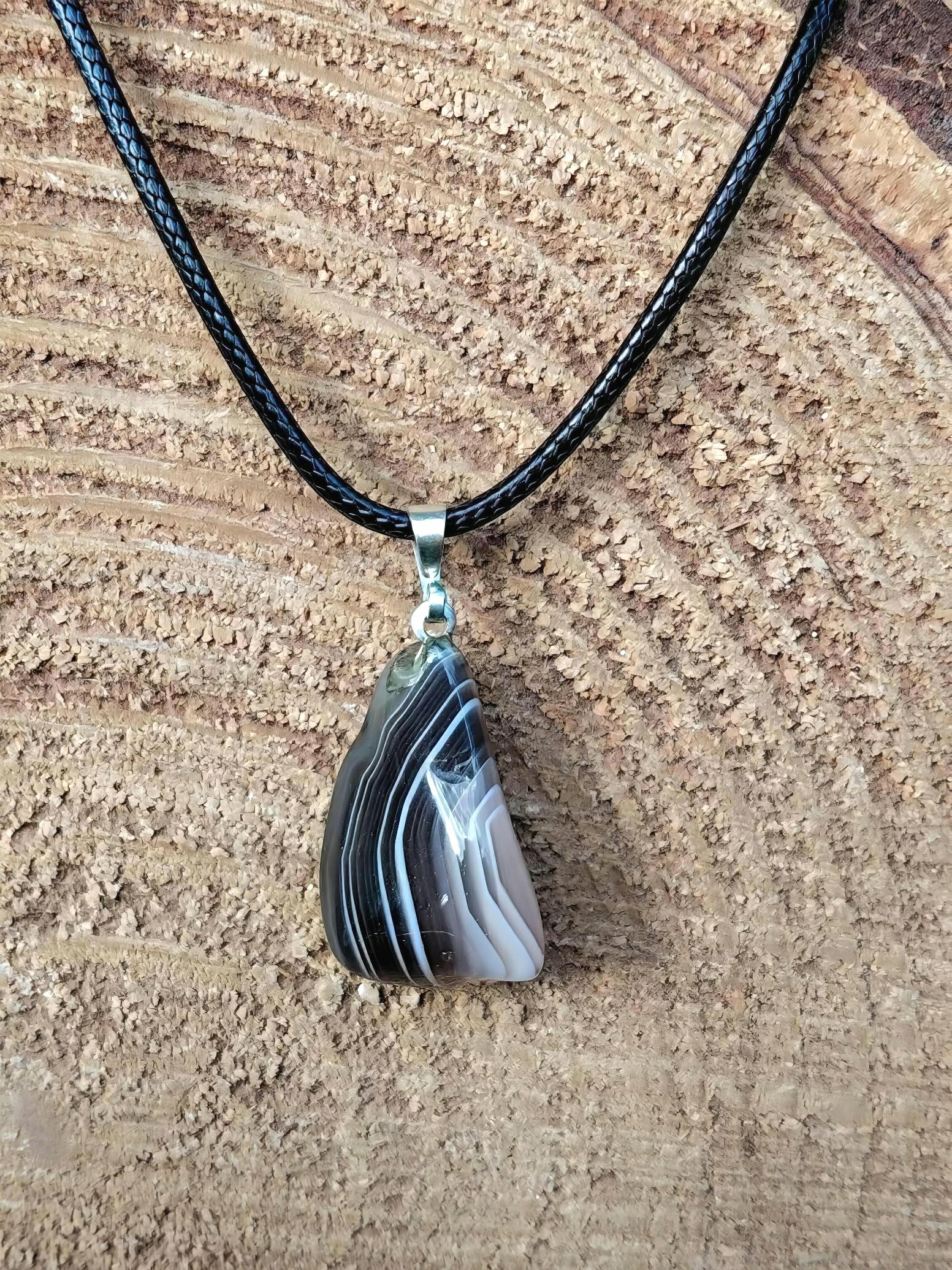 pendentif agate du botswana bandes grises roses en gros plan dans la main, pierre pour apaiser le stress et les émotions