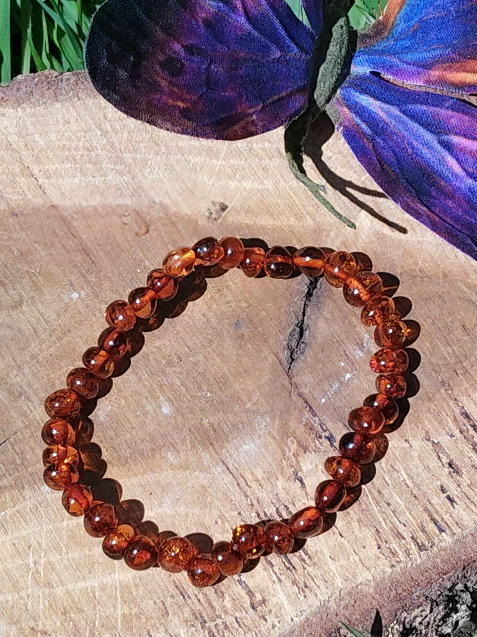 Bracelet en ambre posé près d’un papillon dans une ambiance zen, harmonie intérieure, douceur affective et tensions relâchées