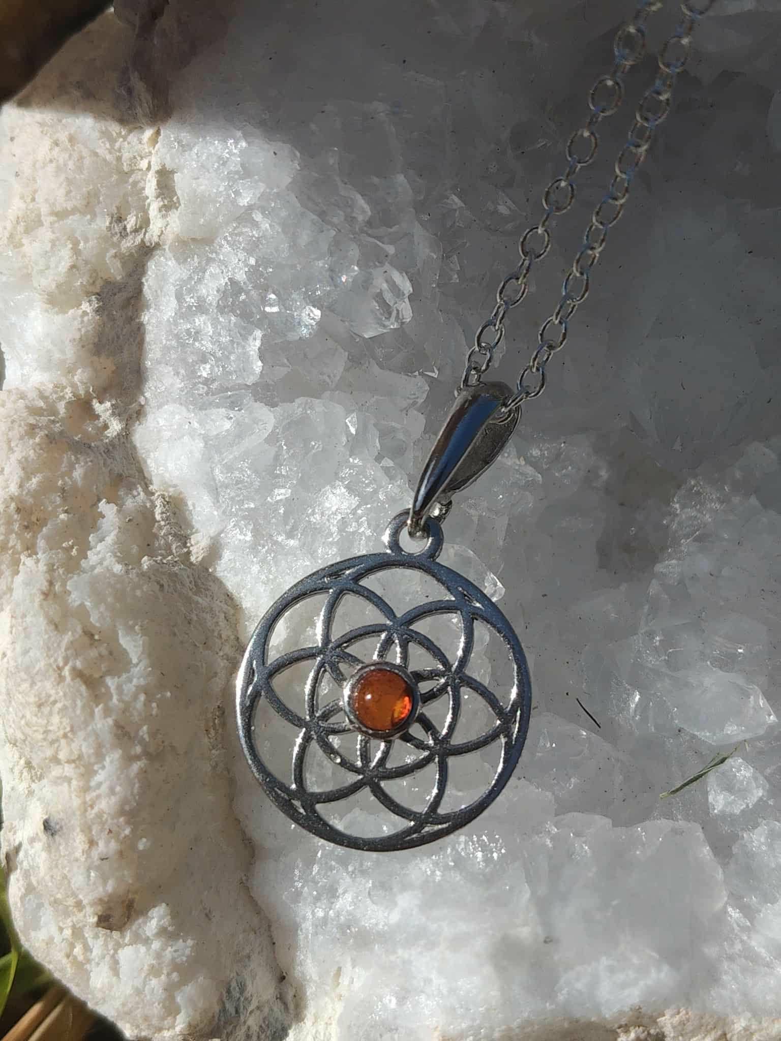Pendentif Fleur de Vie en argent 925 avec perle d’ambre sur fond bois brut, symbole sacré d’alignement et d’apaisement du mental