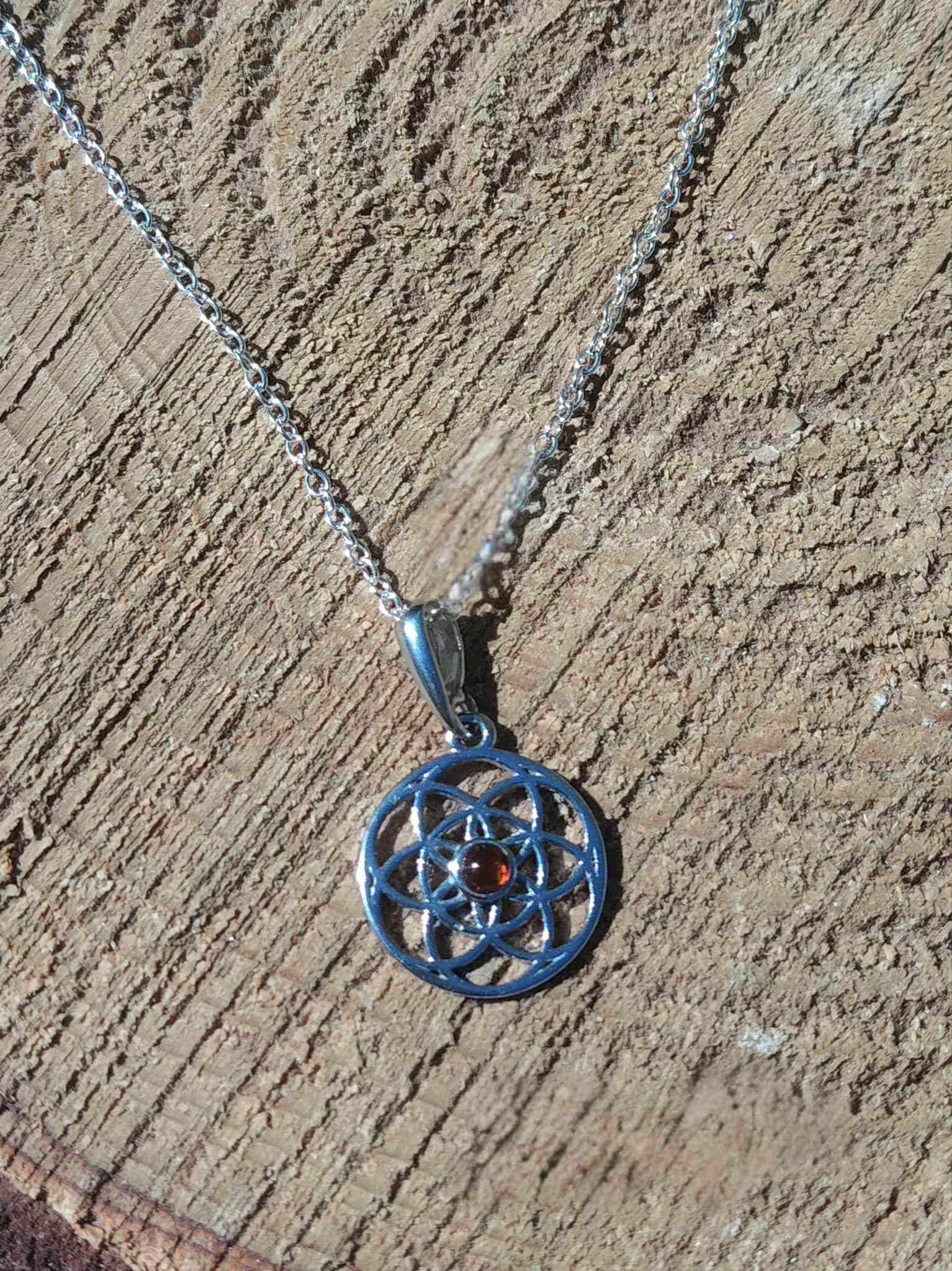 Pendentif Fleur de Vie argent 925 avec perle d’ambre posé sur bois brut, énergie solaire douce et présence apaisée