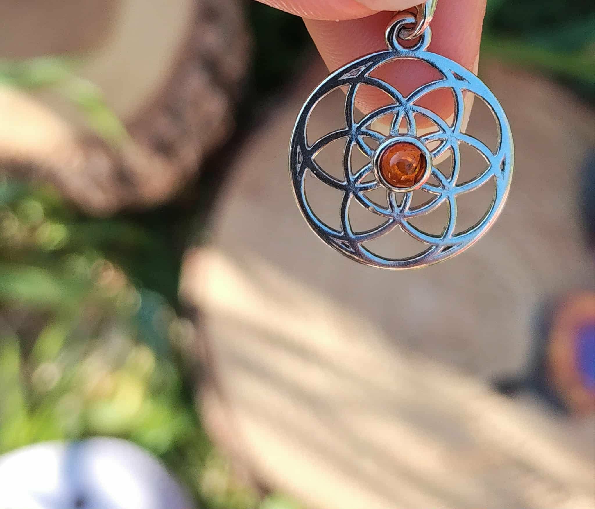 Pendentif Fleur de Vie argent 925 avec perle d’ambre cognac dans un décor nature, symbole d’équilibre et de protection douce