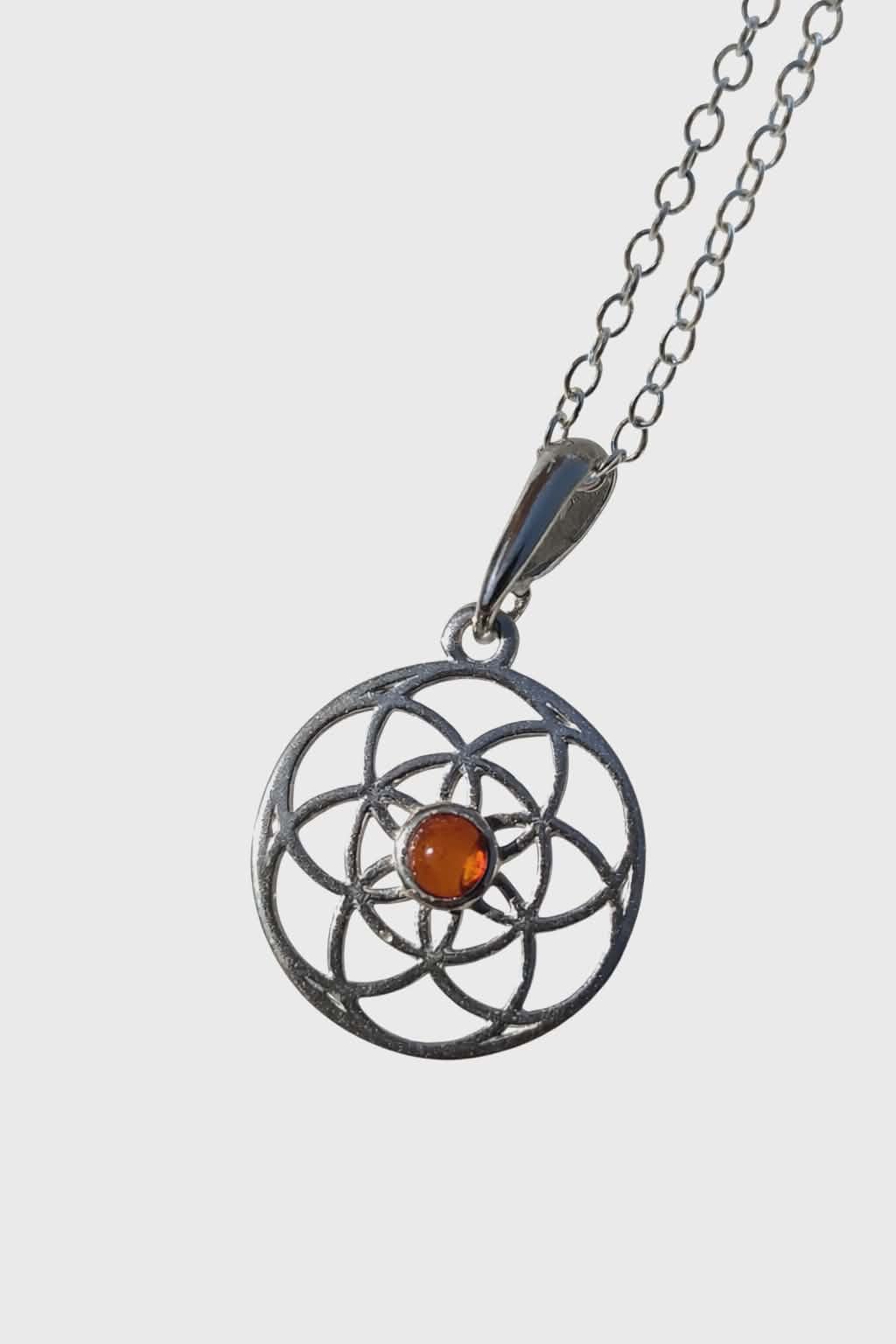 Pendentif Fleur de Vie en argent 925 avec perle d’ambre cognac sur fond blanc, bijou symbolique au style clair et raffiné