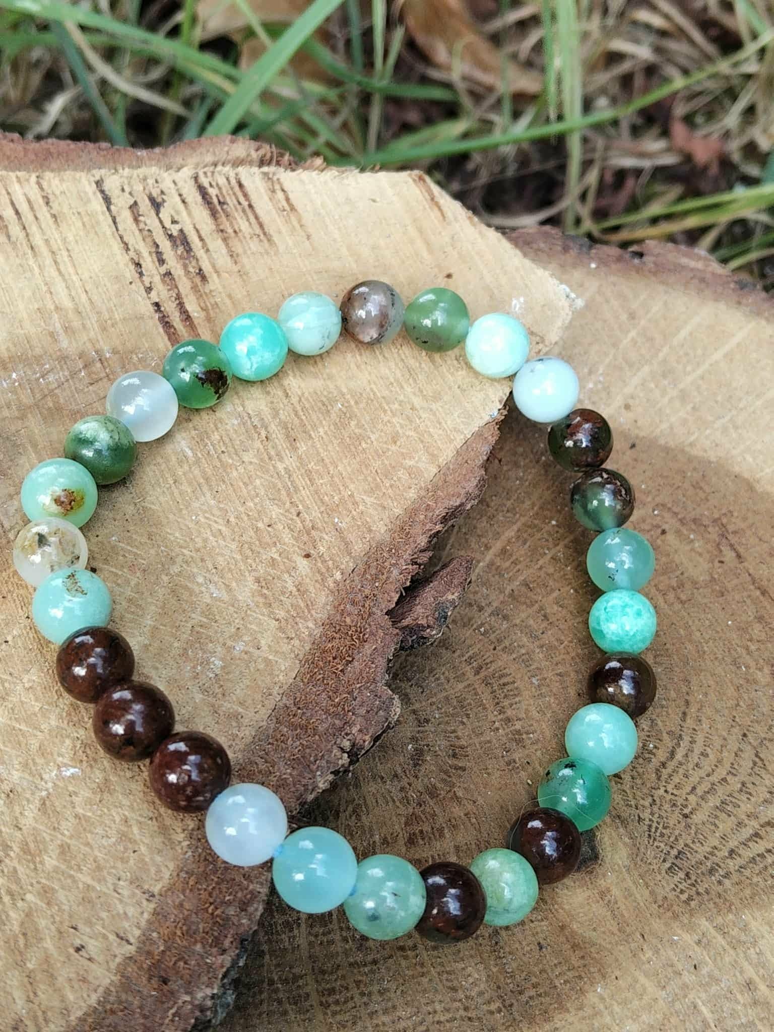 Bracelet chrysoprase posé sur planche en bois avec herbes et terre, pierre naturelle pour relâchement du mental et paix intérieure