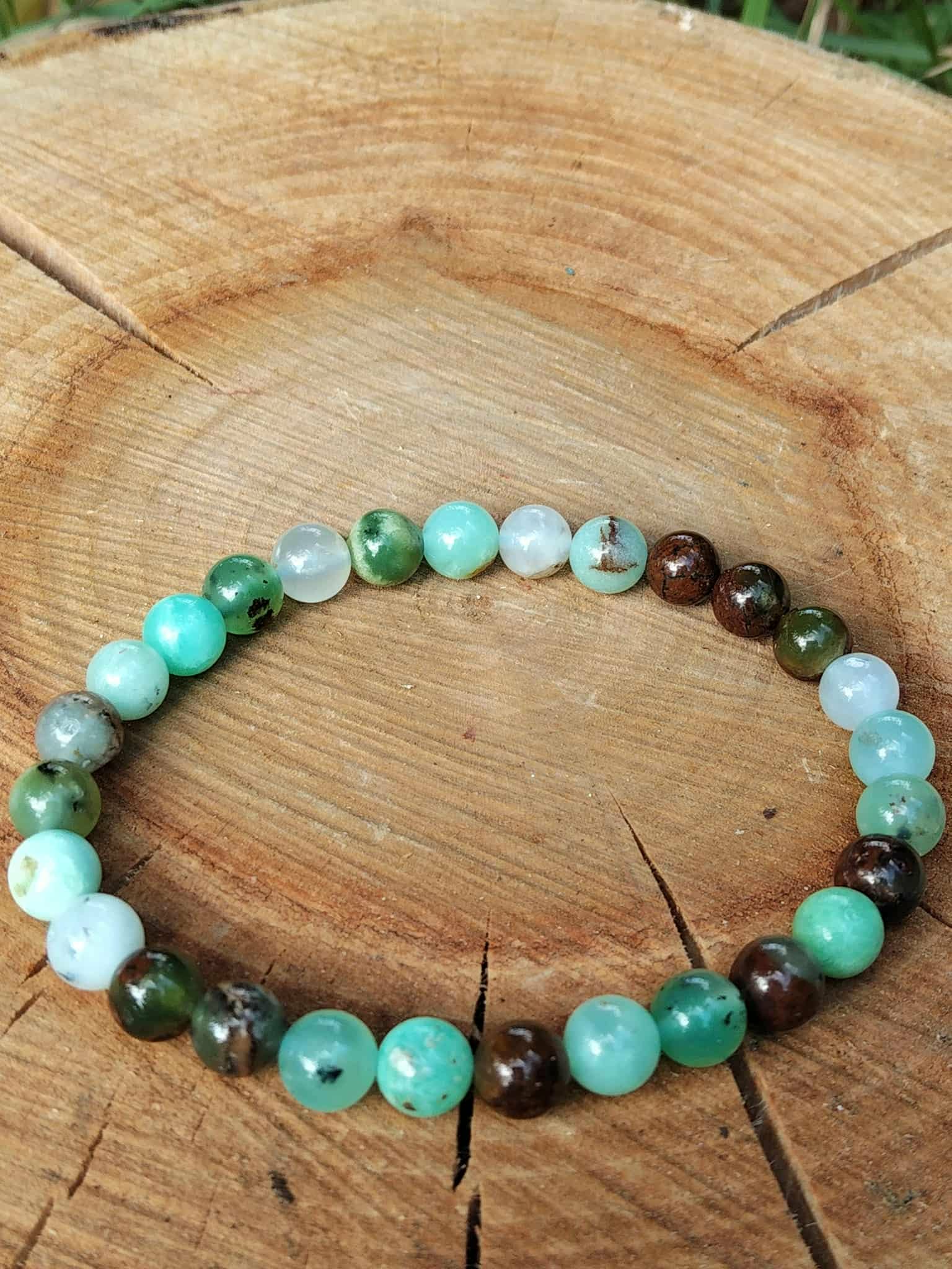 Bracelet chrysoprase posé sur grande tranche de bois fendu, perles vertes et marron pour apaiser les tensions et retrouver la sérénité