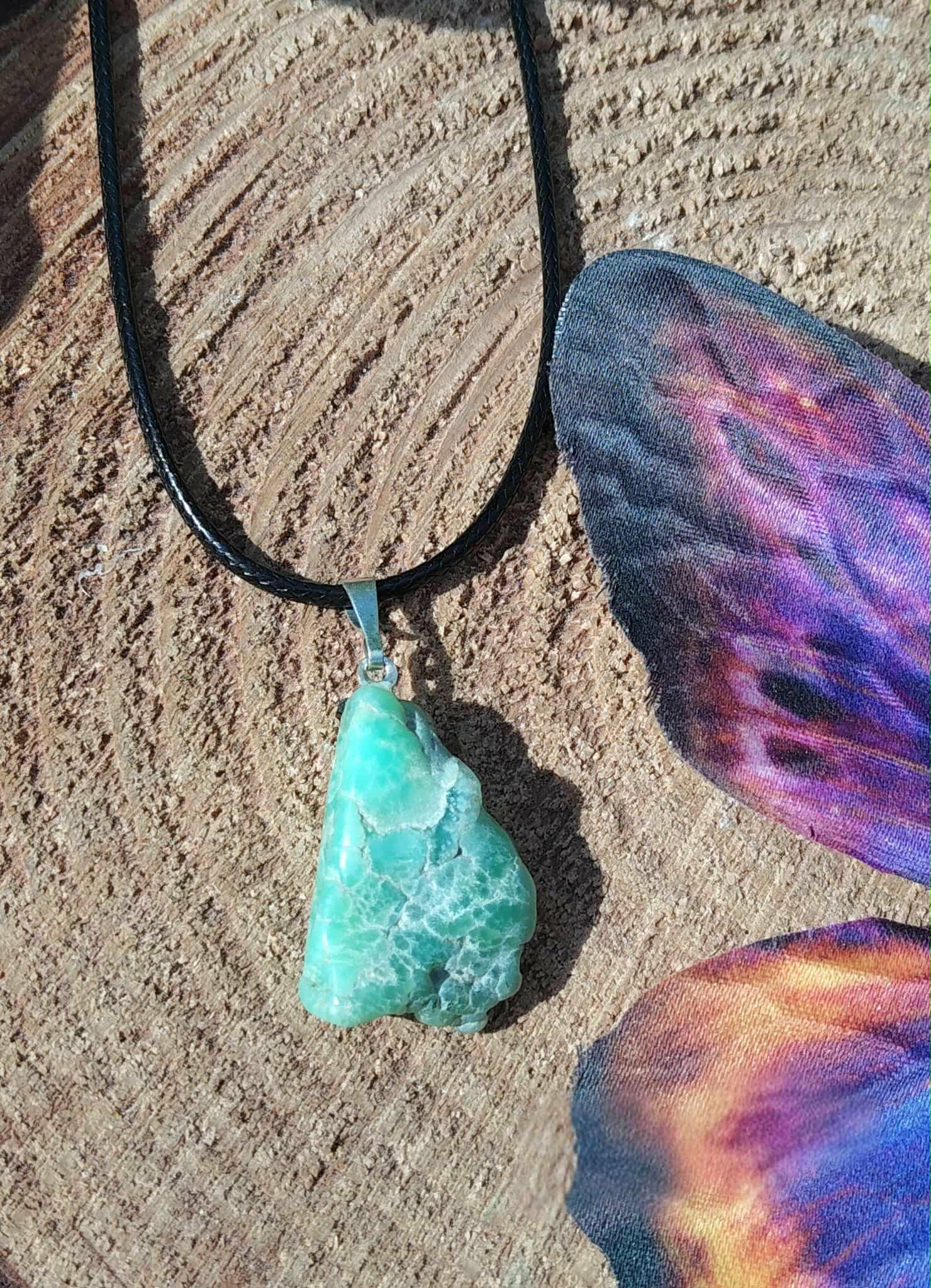 Pendentif chrysoprase pierre brute verte sur bois avec papillon violet, pierre naturelle reliée au lâcher-prise, à la respiration émotionnelle et à la tranquillité du cœur.