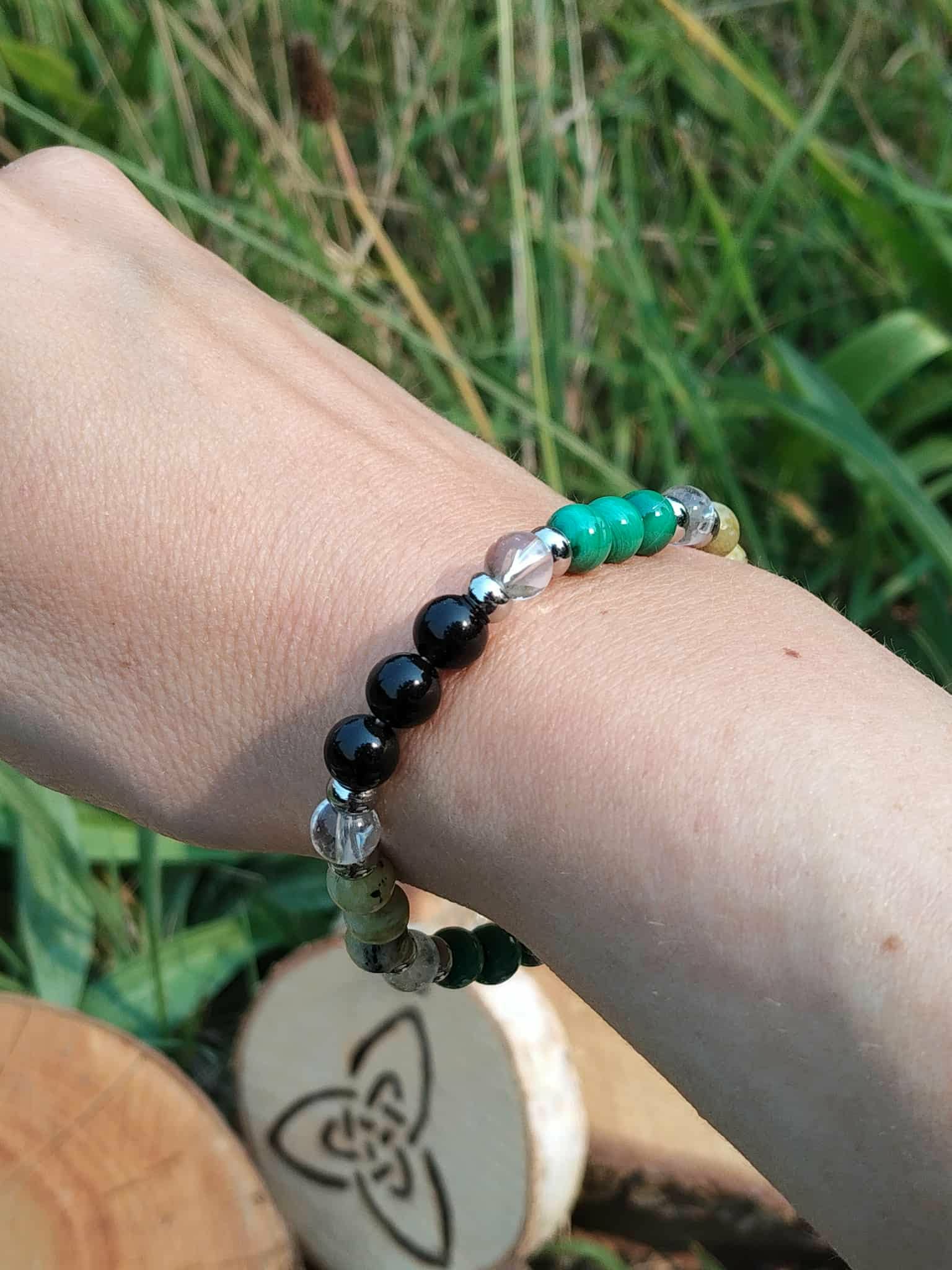 Bracelet Fibromyalgie porté sur fond végétal, pierres naturelles pour stabilité émotionnelle et sensation d’appui intérieur