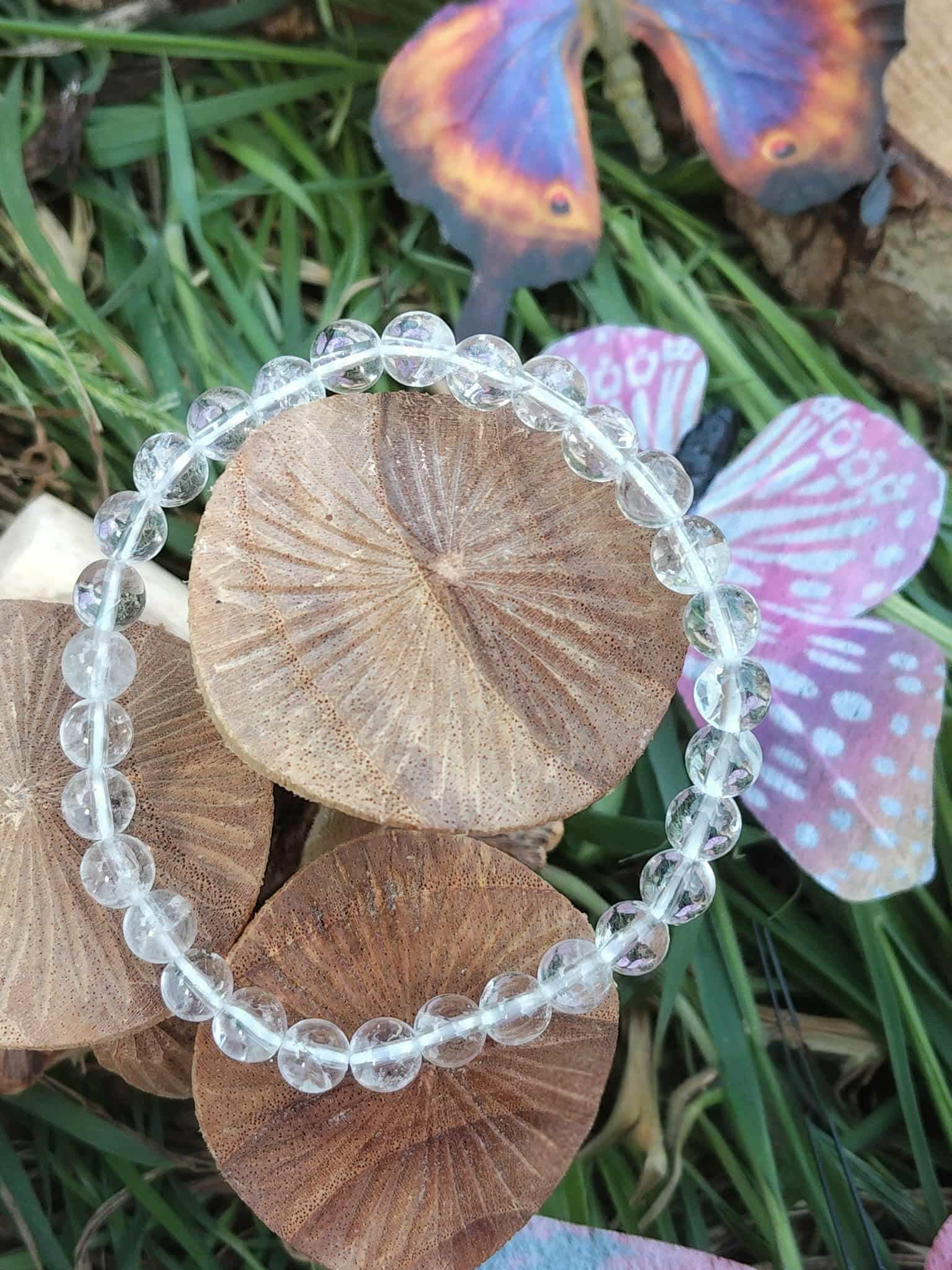 Bracelet cristal de roche 6 mm autour de champignons en bois avec feuillage vert et papillon violet, intuition fine et ouverture subtile