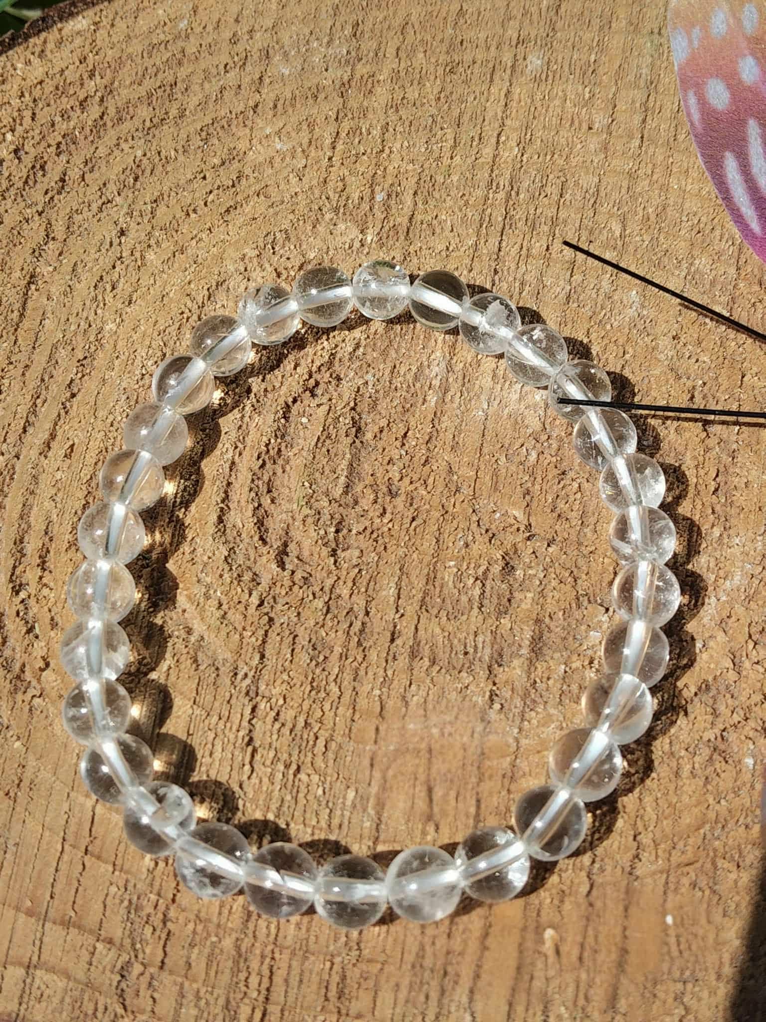 Bracelet cristal de roche 6 mm en cercle sur fond bois chaud, style photo produit pour apaisement mental et sérénité intérieure