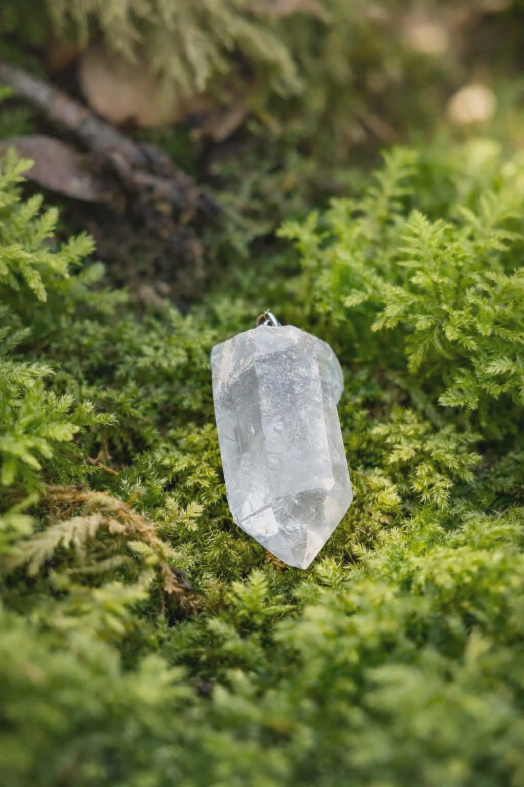 Porte-clés / bijou de sac en cristal de roche taillé en pointe facettée, posé sur mousse verte en décor forêt, ambiance nature féerique – Magic Gaïa