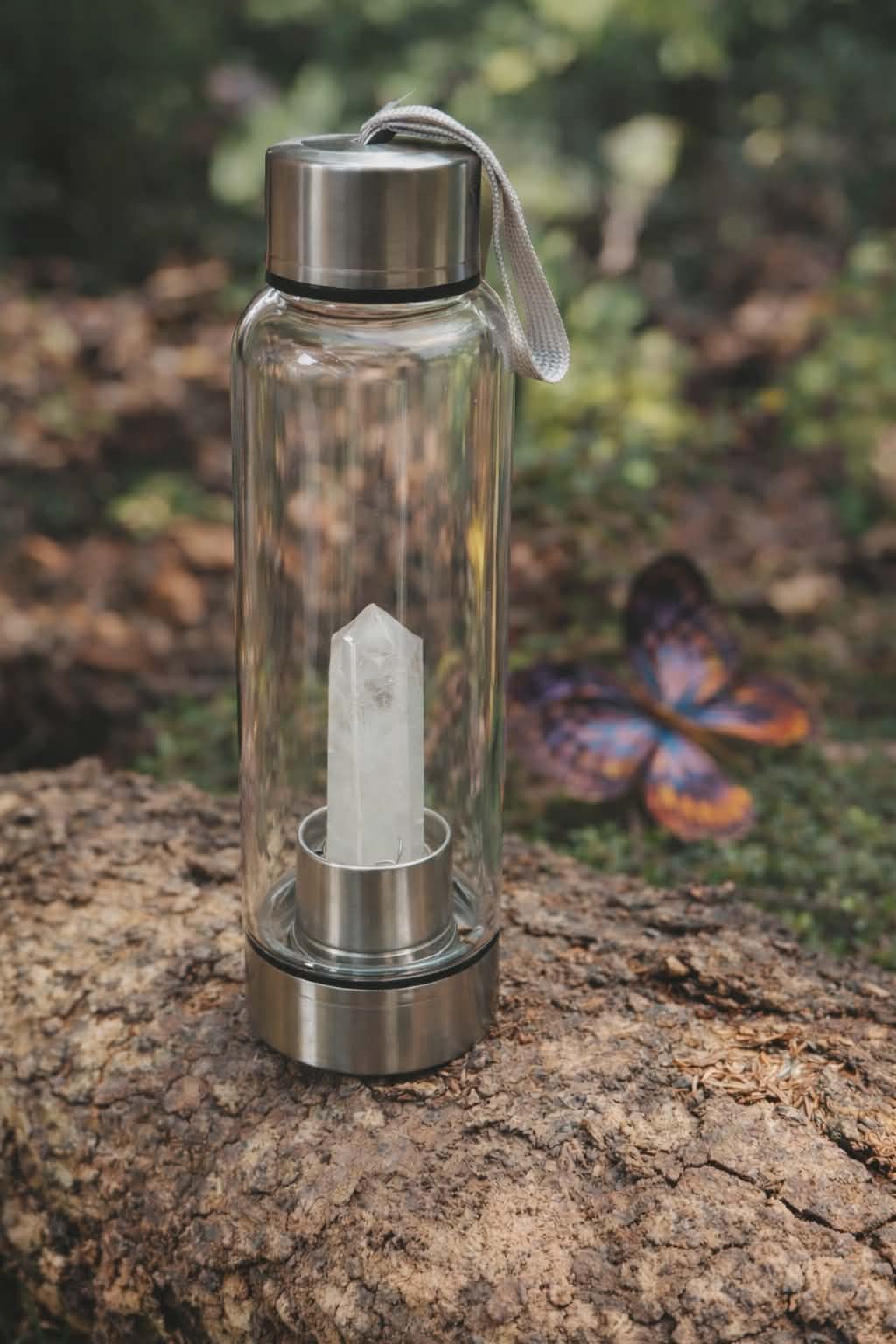 bouteille deau en verre énergisant cristal de roche, 500 ml, verre transparent avec bouchon inox et dragonne, pointe de cristal de roche intégrée, photo sur tronc en décor nature