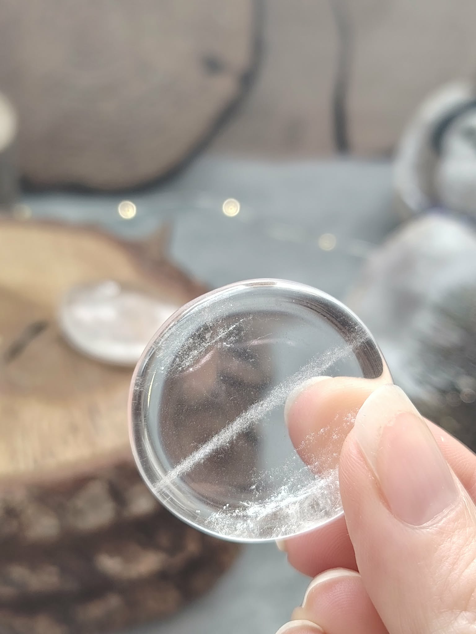 galet cristal de roche poli tenu entre les doigts, pierre roulée transparente avec inclusions naturelles, photo en gros plan