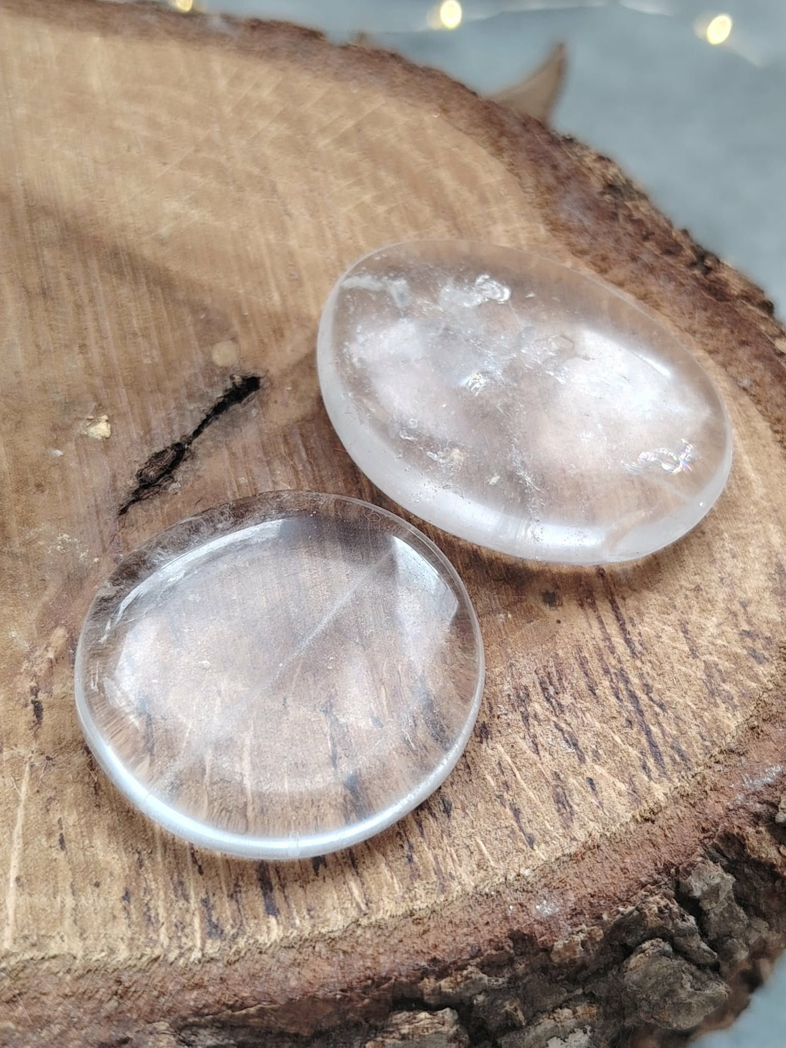 Galet cristal de roche poli tenu entre les doigts en gros plan, pierre roulée transparente avec inclusions naturelles évoquant la lucidité, le recentrage et la paix du mental.
