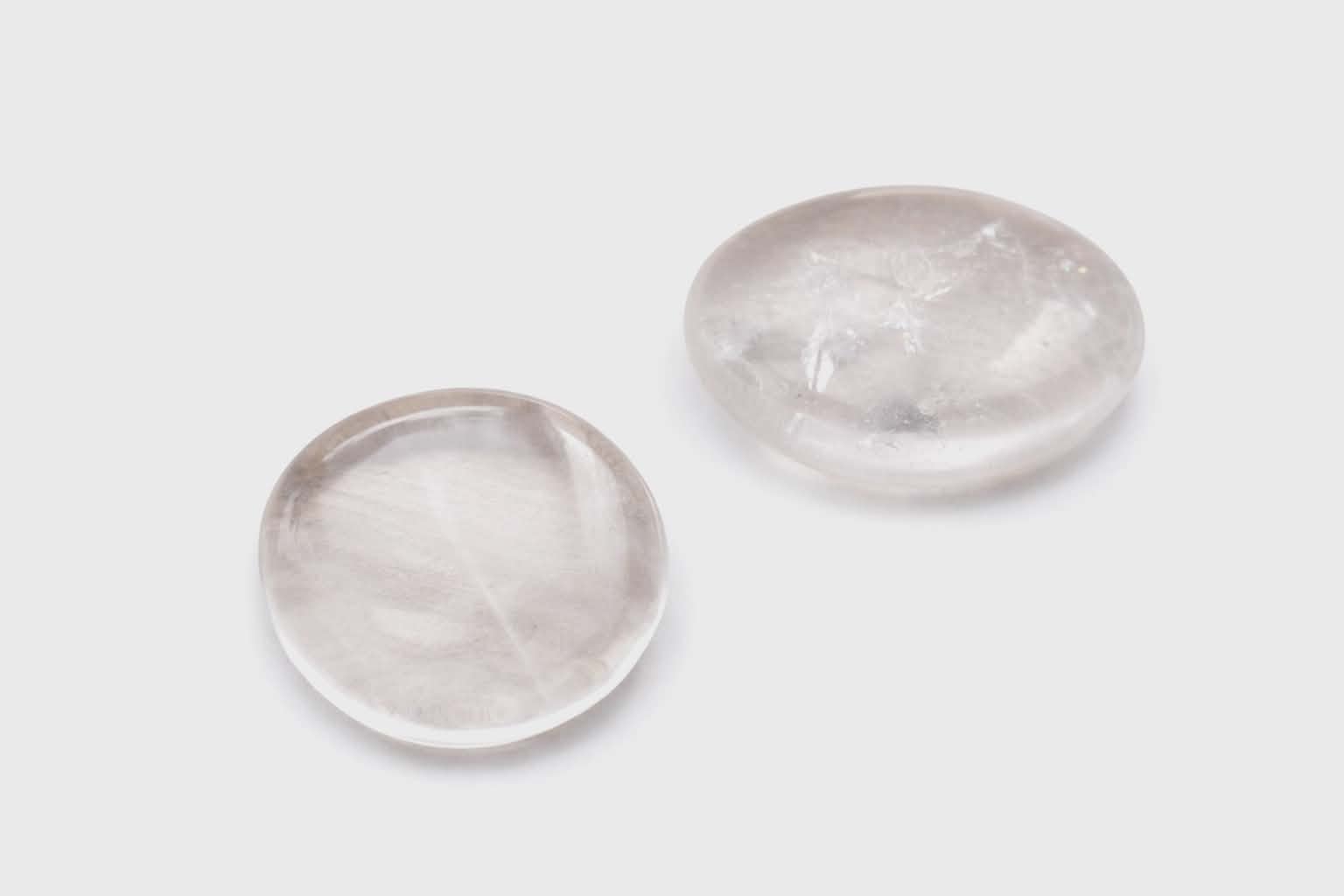 Galet cristal de roche poli sur fond blanc, pierre translucide avec inclusions naturelles en vue rapprochée, associé à la transparence, à l’apaisement et à la précision mentale.