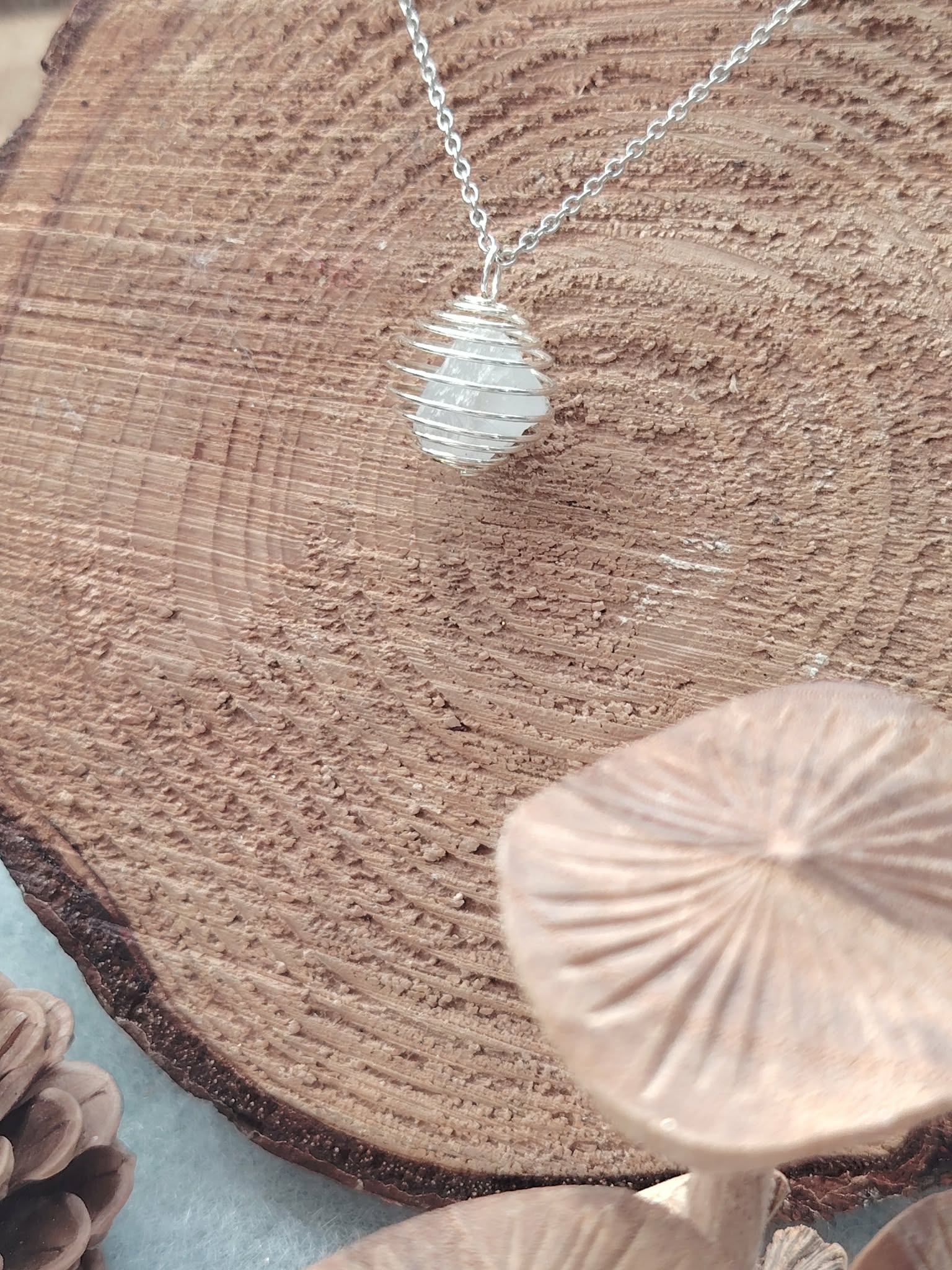 Pendentif avec pierre blanche/translucide, chaîne acier inoxydable, photo produit sur support bois brut, amplification des énergies