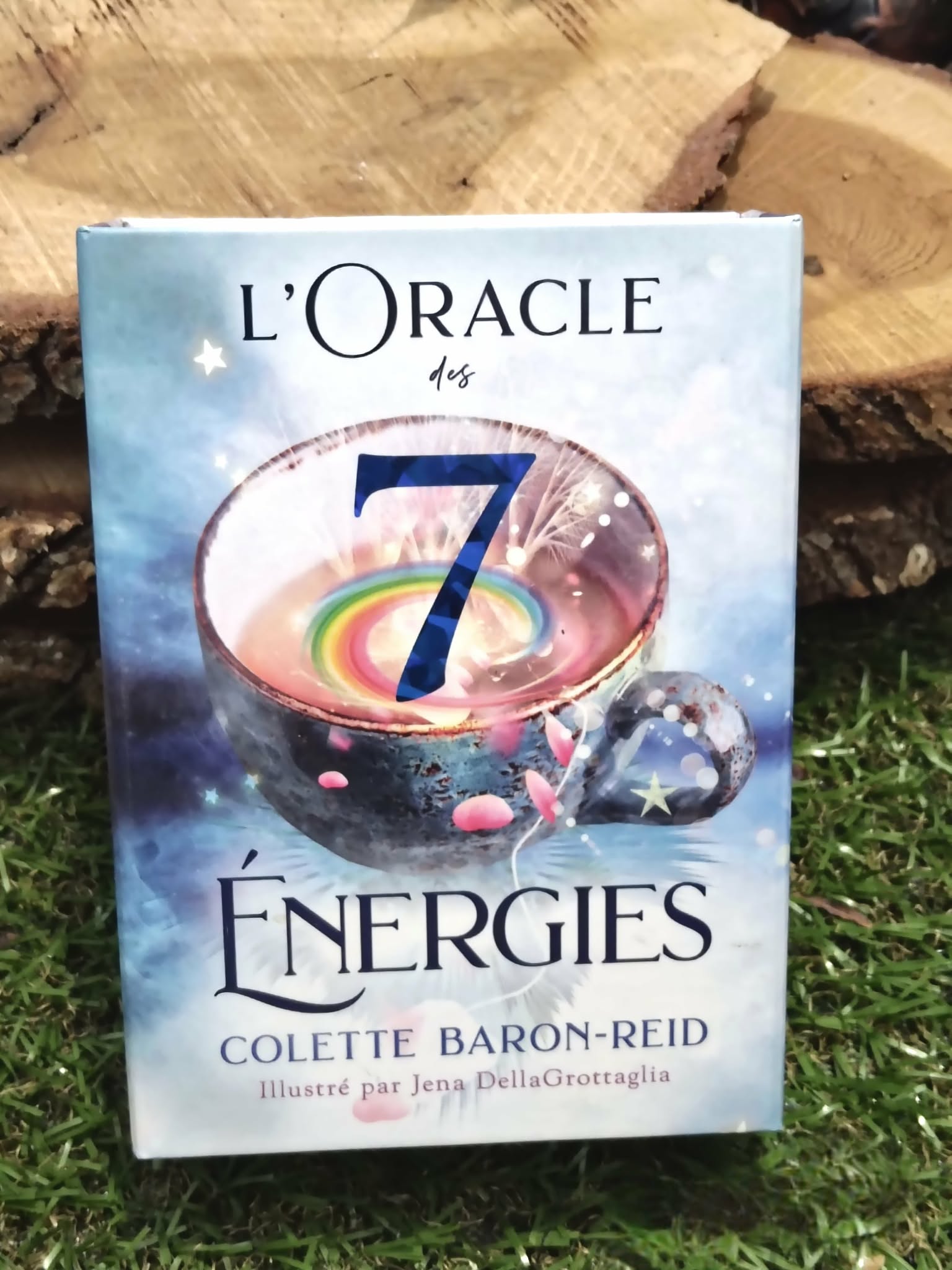 L’Oracle des 7 Énergies (Colette Baron-Reid) – coffret divinatoire en français, boîte vue de face posée sur surface naturelle type pierre/bois, ambiance ésotérique.