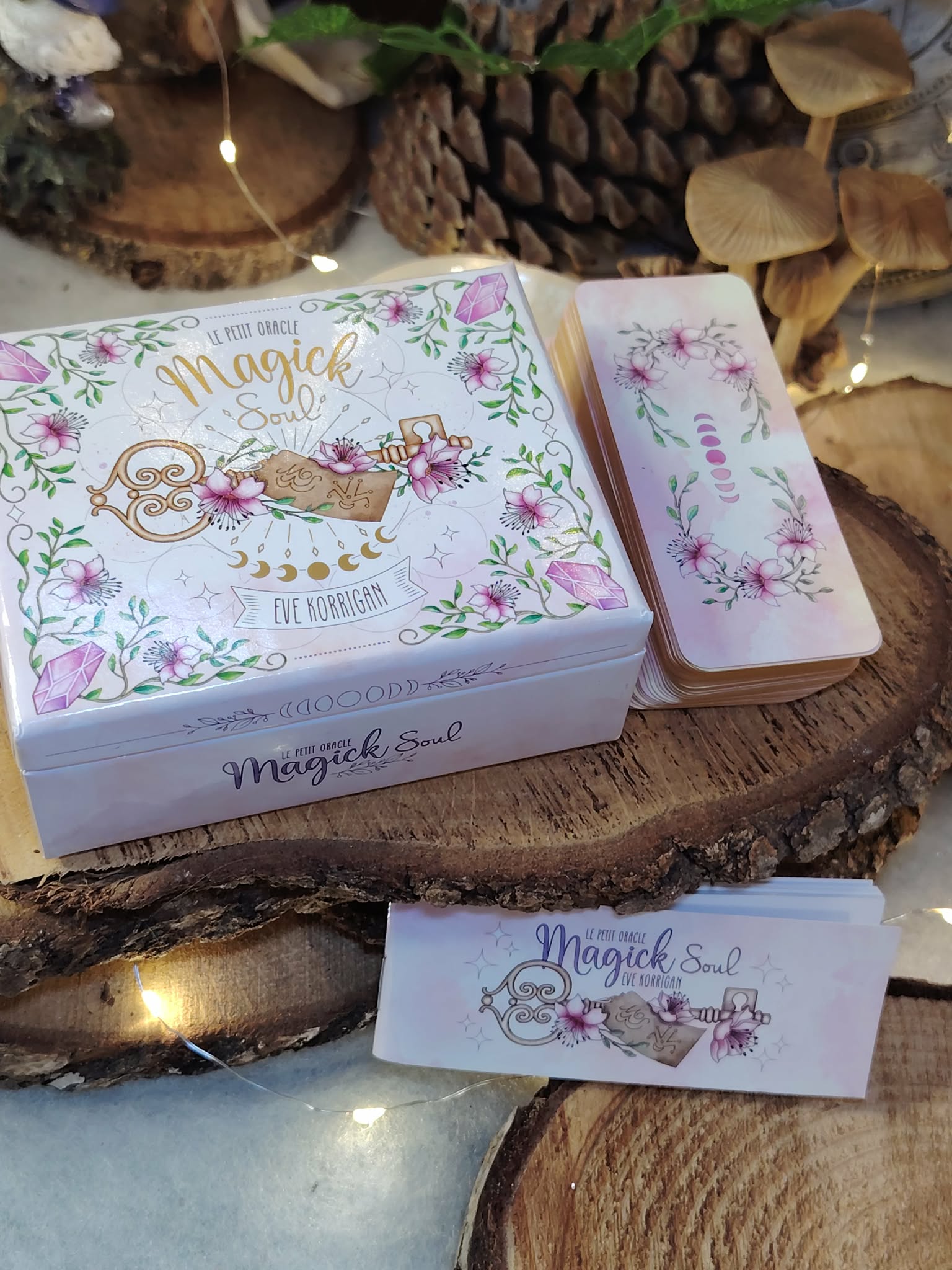 Petit Oracle Magic Soul (boîte et cartes) posé sur plateau en bois, décor rondins empilés et lumière chaleureuse, ambiance ésotérique.