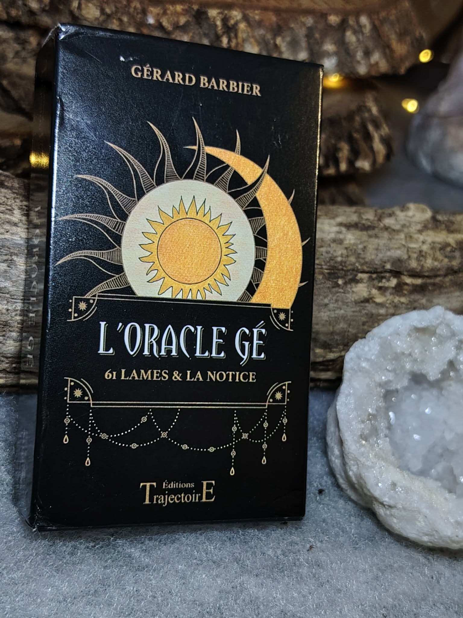 Oracle Gé Éditions Trajectoire en présentation, fond bois et guirlande lumineuse, ambiance mystique