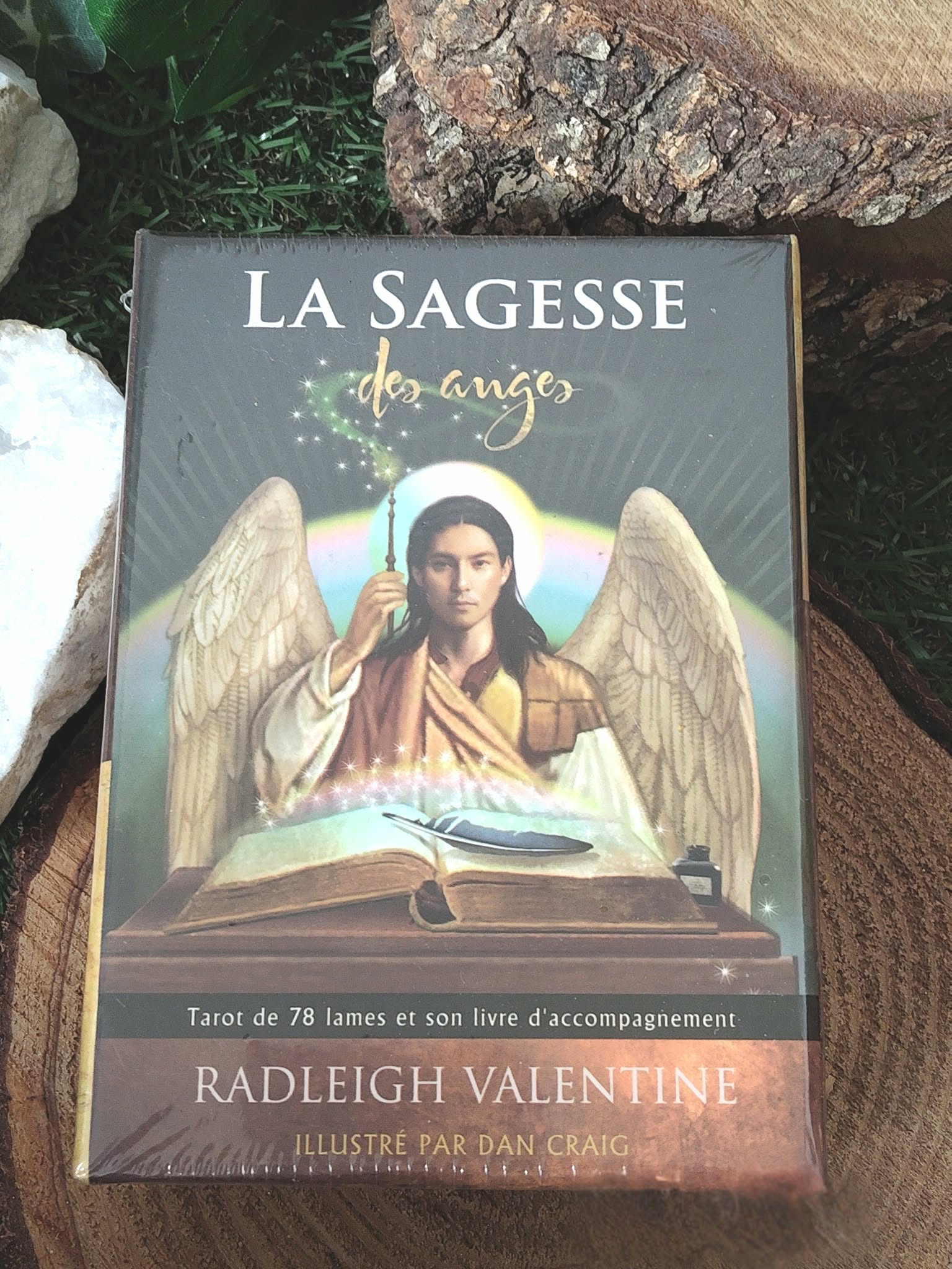 La Sagesse des Anges (Radleigh Valentine) : boîte du tarot avec ange ailé, posée sur rondin de bois en décor naturel.