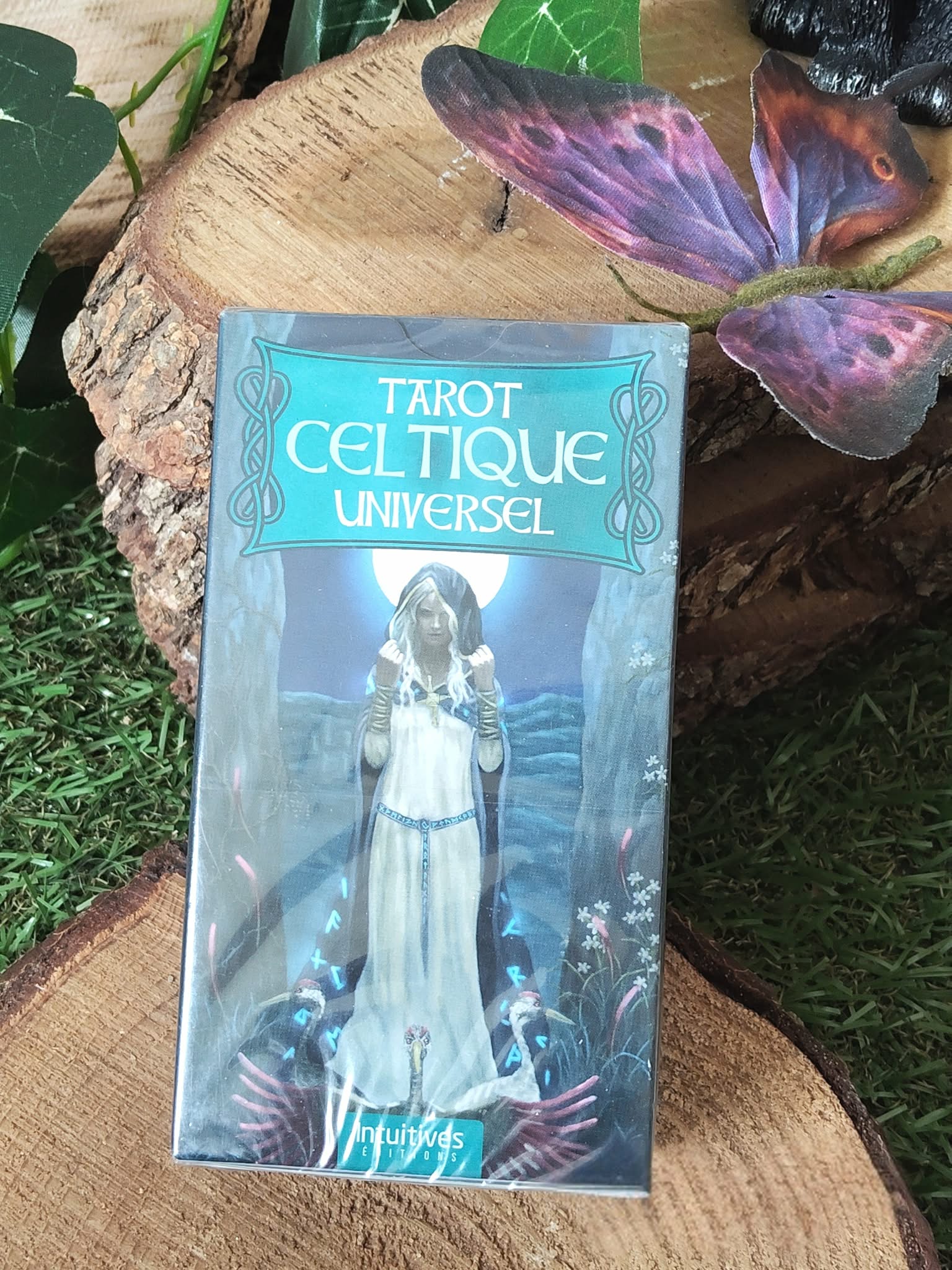 Tarot divinatoire Celtique Universel – boîte du jeu sur support bois, décor végétal et papillon en arrière-plan