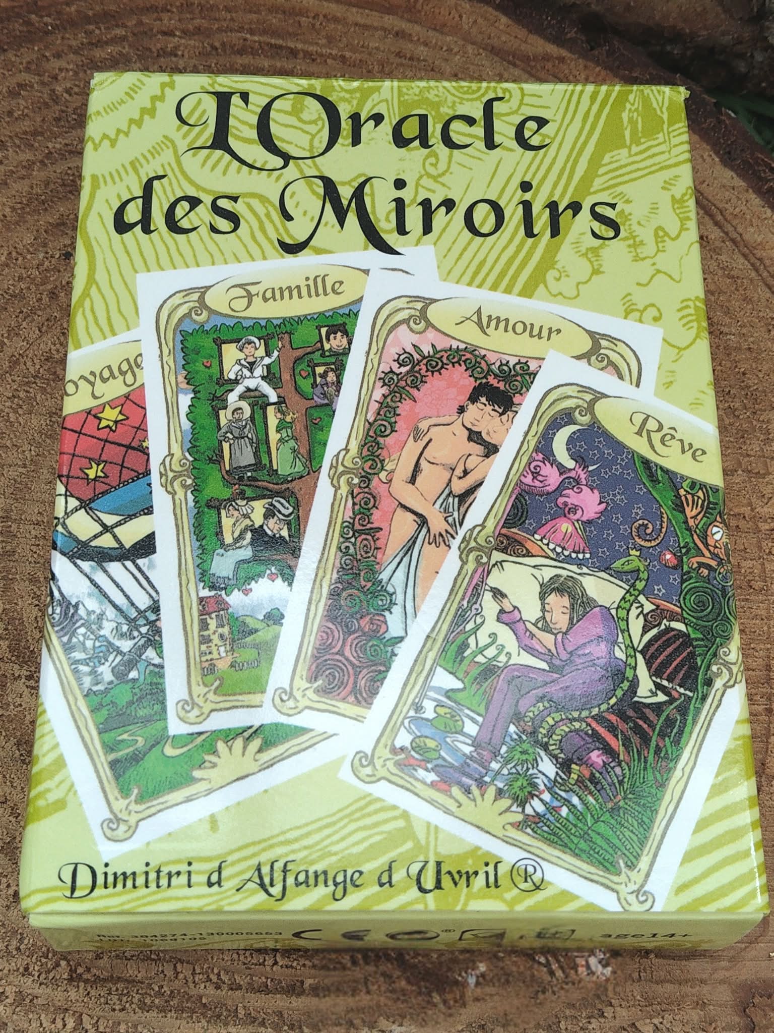 Oracle des miroirs, coffret de 53 cartes divinatoires   livret, boîte vue de face en gros plan sur fond bois naturel.