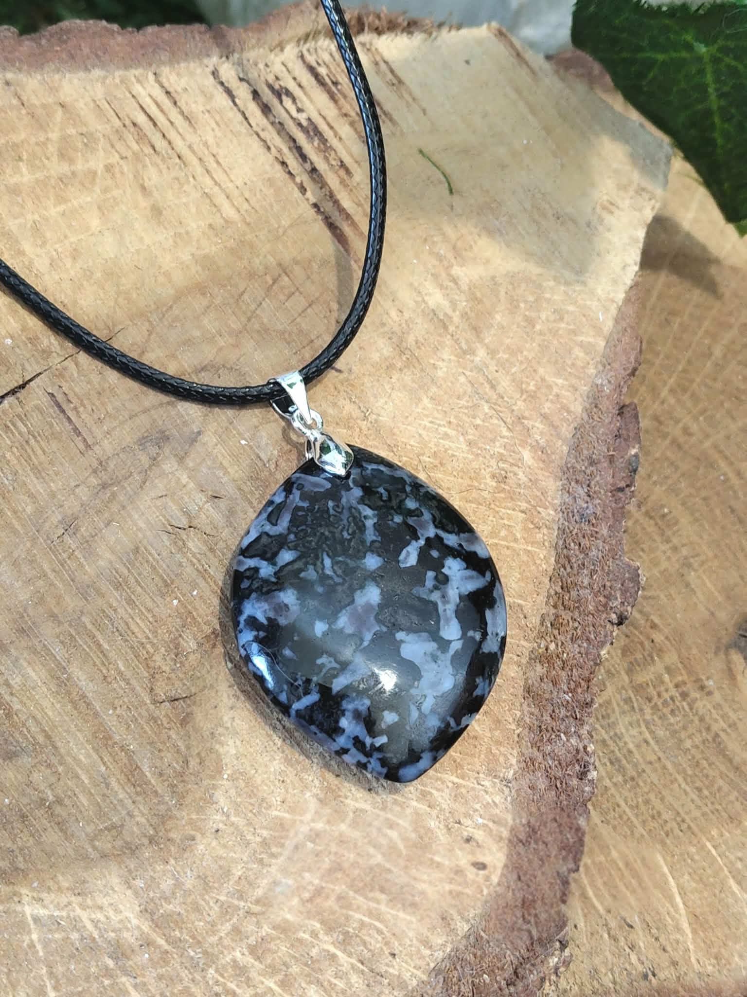 Bijou pendentif goutte en gabbro sur décor bois naturel, pierre sombre aux motifs uniques évoquant la protection, l’enracinement et la concentration intérieure.