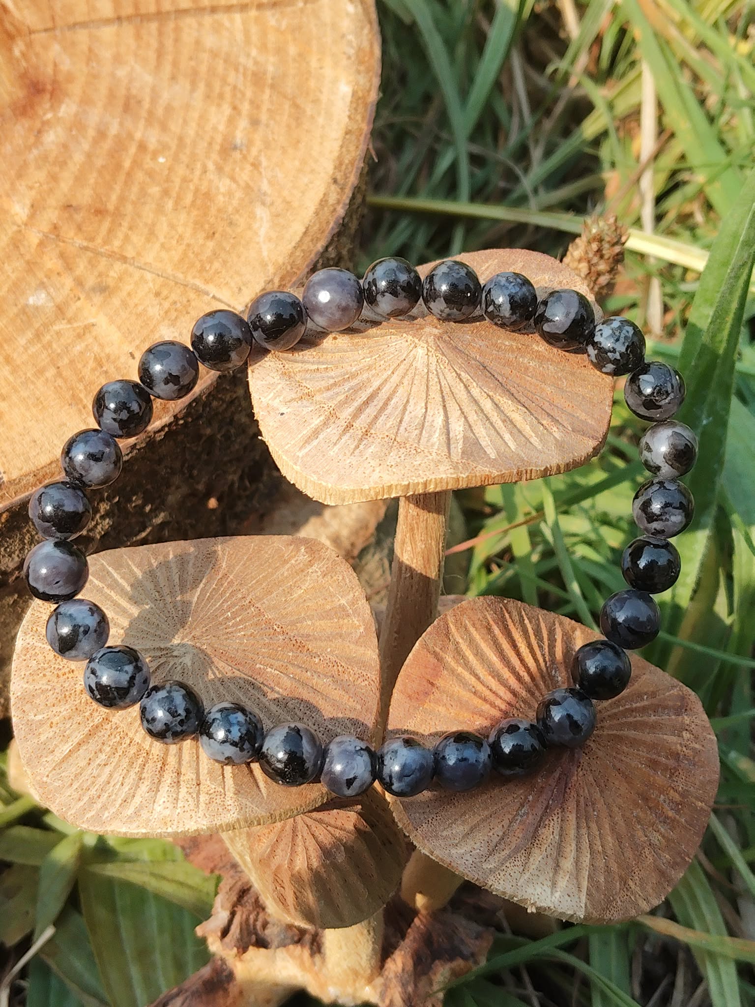 Bracelet Gabbro sur rondins de bois, décor forêt et verdure, bijou lithothérapie associé au recentrage et à la confiance