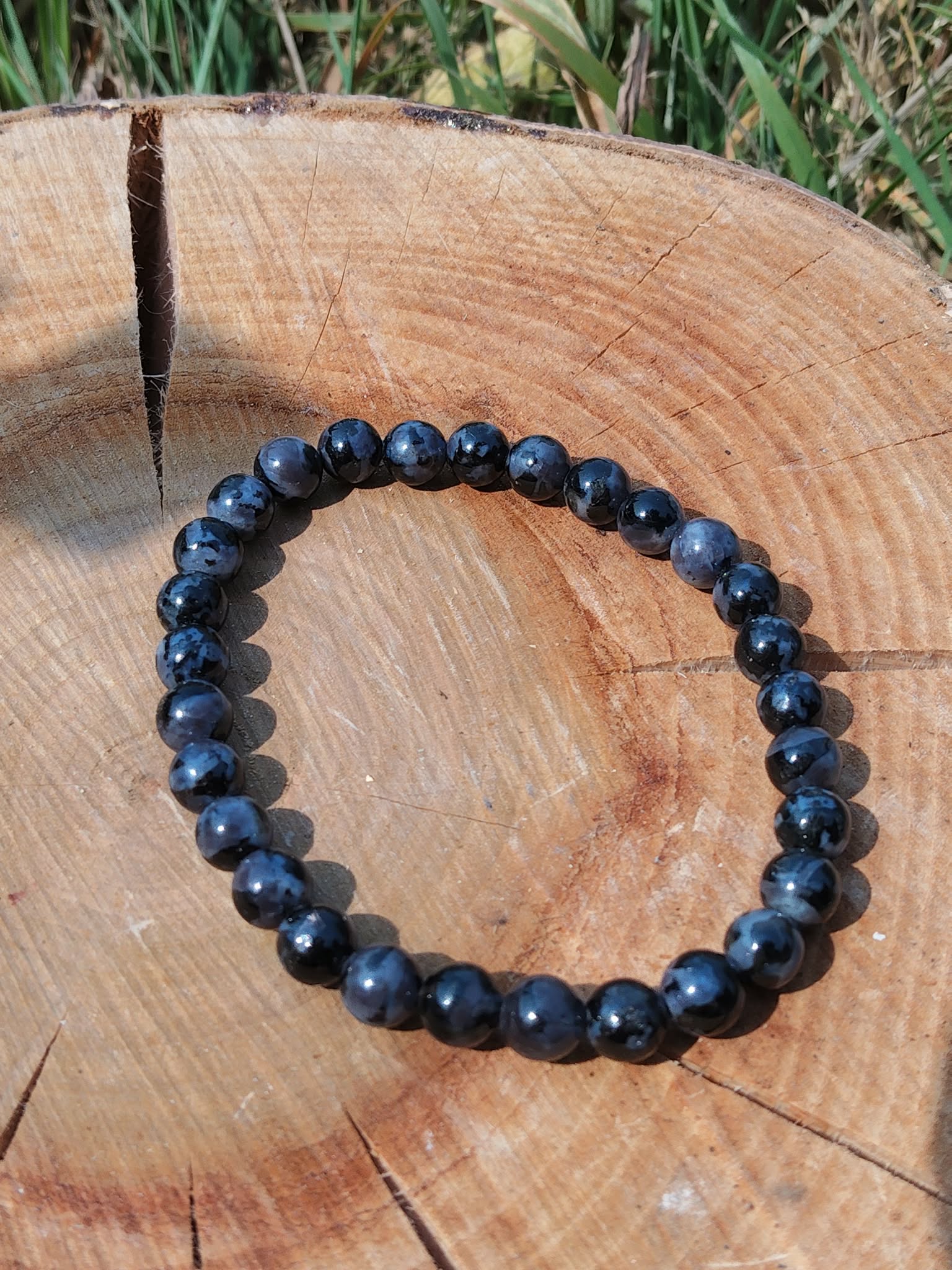 Bracelet Gabbro bleu-noir en cercle sur tranche de bois, décor nature, bijou énergétique pour apaisement mental et recentrage