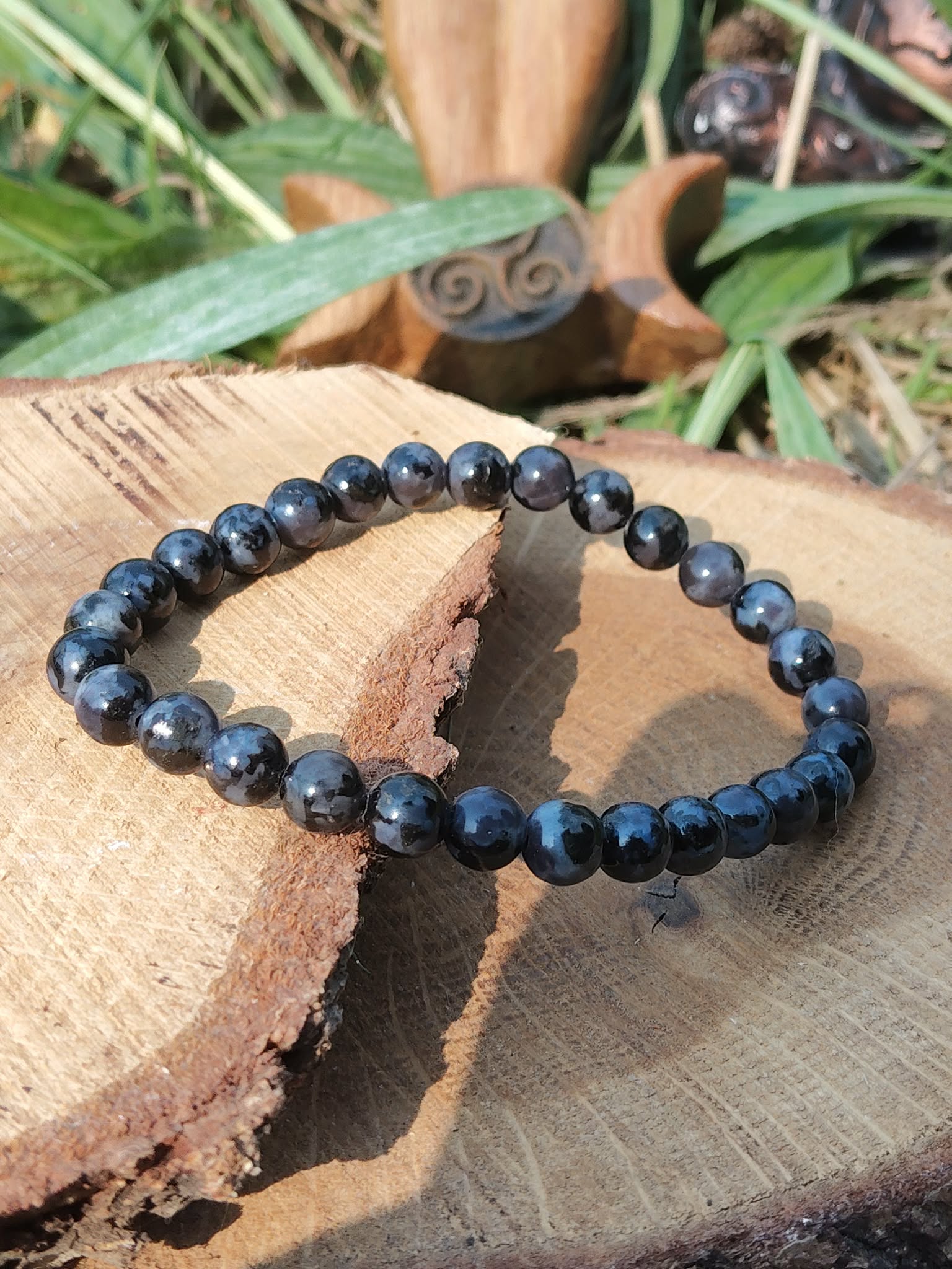 Bracelet Gabbro indigo sur bois naturel, ambiance végétale, pierre d’introspection et de transformation intérieure.