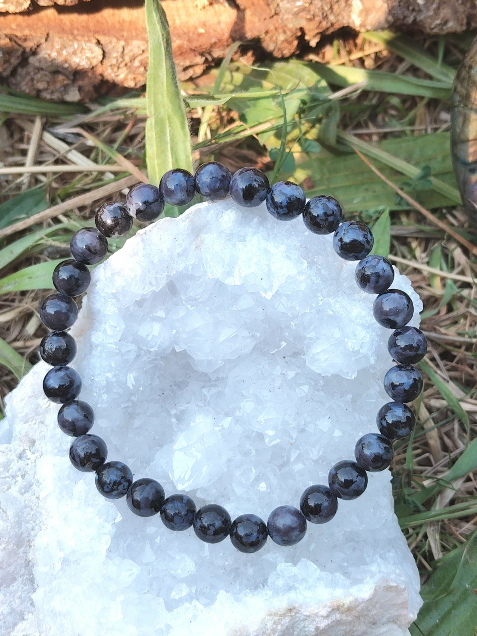 Bracelet Gabbro sombre aux reflets bleutés sur pierre claire, photo nature, pierre de protection et d’ancrage