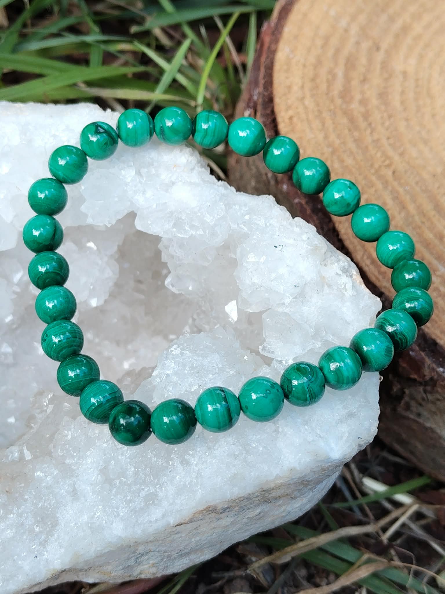 Bracelet malachite 6 mm posé sur amas de quartz blanc, contraste minéral et vert profond, protection douce et clarté émotionnelle