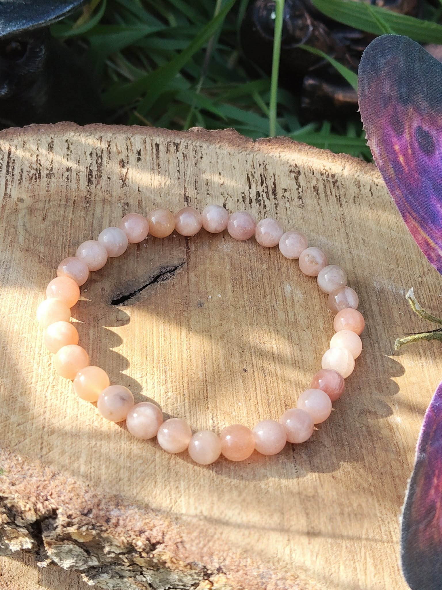 Bracelet 6 mm  pierre de soleil (reflets cuivrés) sur tranche de bois, décor végétal et élément violet ; bijou bien-être pour dynamisme, bonne humeur, passage à l’action.