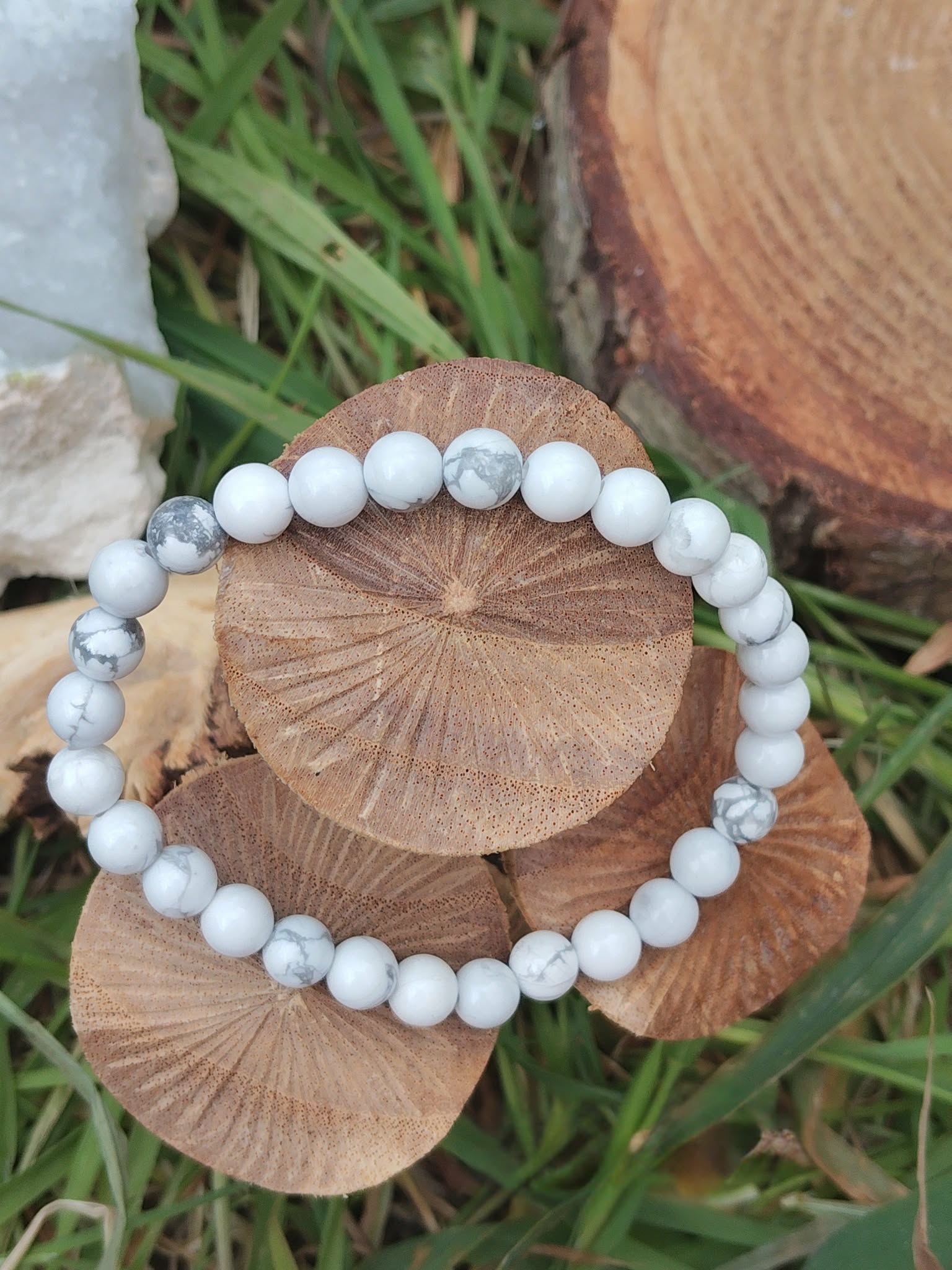 Bracelet howlite blanche 6 mm sur tranche de bois avec fond végétal et décor gravé, perles blanches veinées de gris, patience, stabilité et paix intérieure.