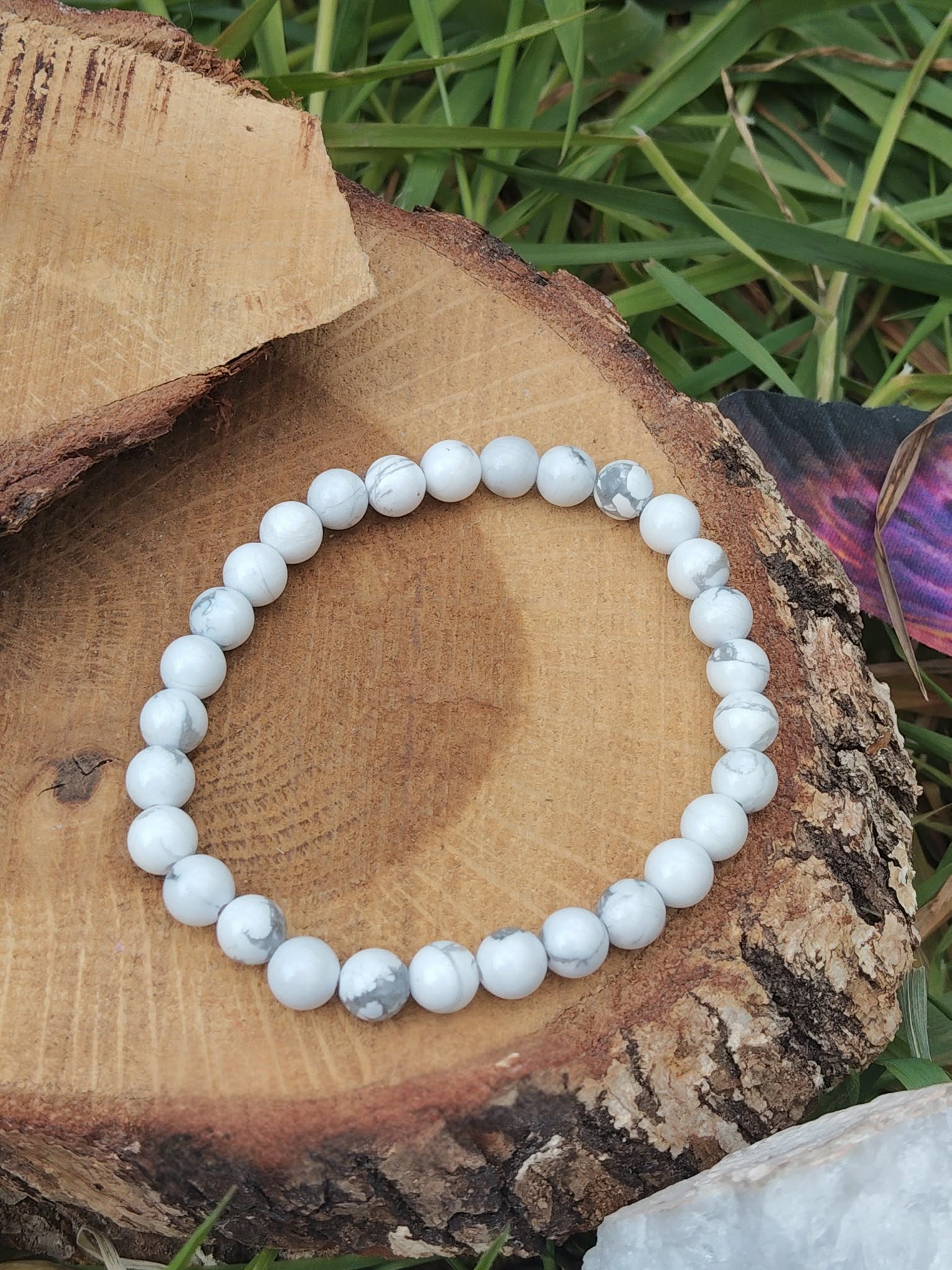 Bracelet howlite blanche 6 mm en cercle sur tranche de bois avec herbe, marbrures grises naturelles, détente mentale et endormissement plus serein