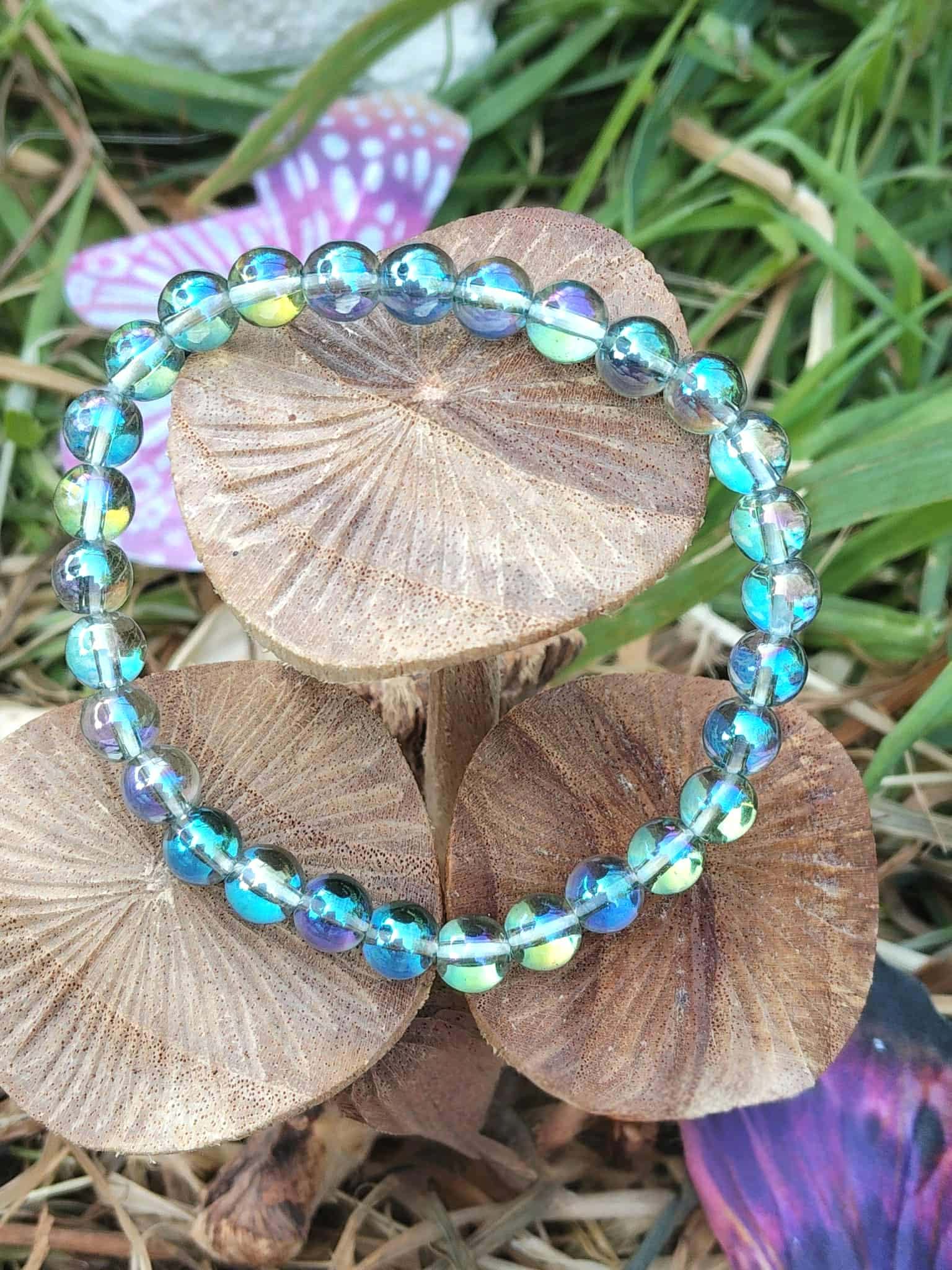 Bracelet Aqua Aura sur bois naturel avec feuillage, perles lumineuses aux reflets aqua, apaisement des pensées et retour à soi