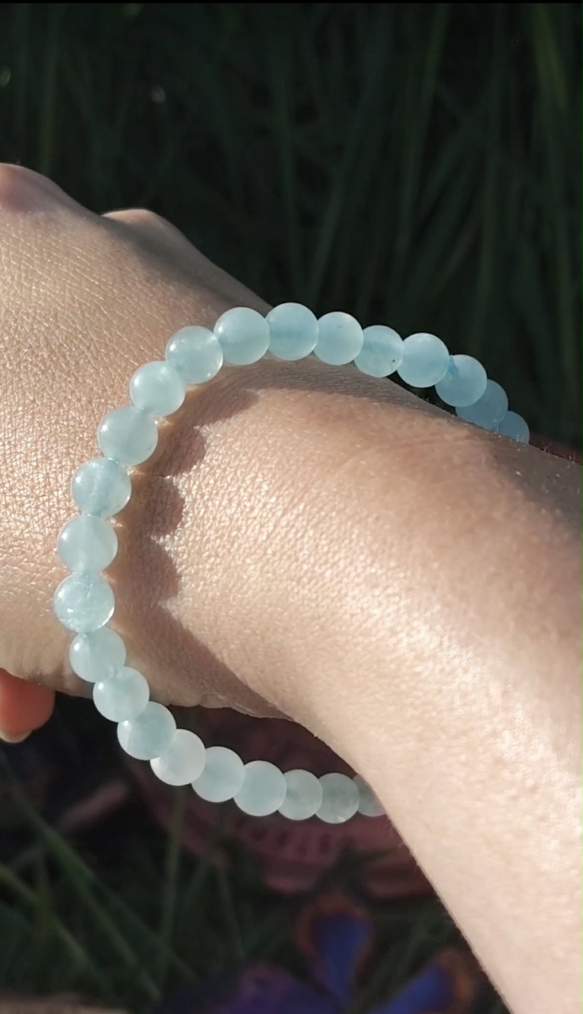 Bracelet Aigue-Marine 6 mm porté à la main, perles bleu océan en gros plan, détente intérieure et relâchement émotionnel.