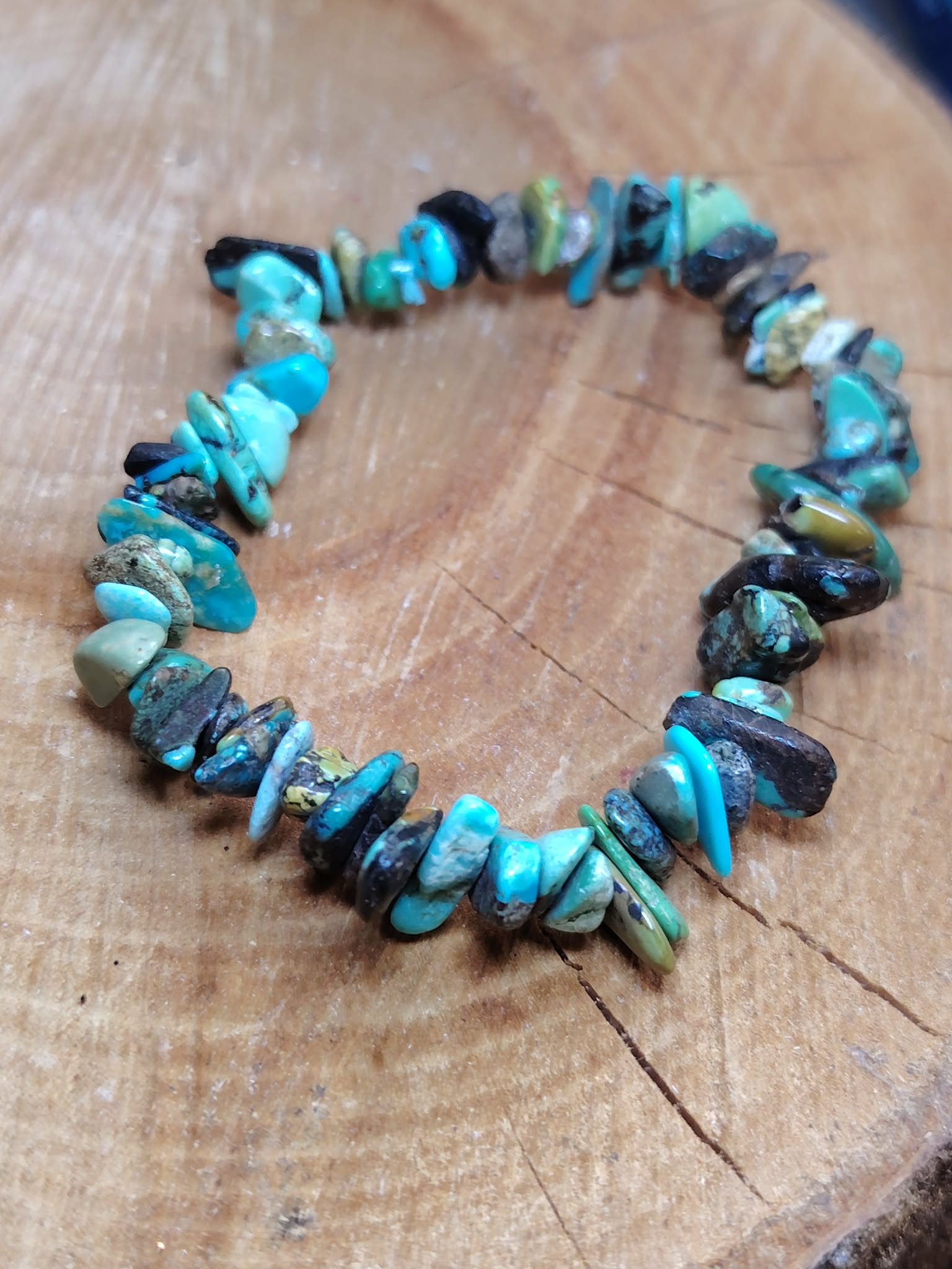 Bracelet turquoise baroque sur élastique posé en cercle sur planche de bois brut, communication apaisée, harmonie relationnelle et protection en déplacement