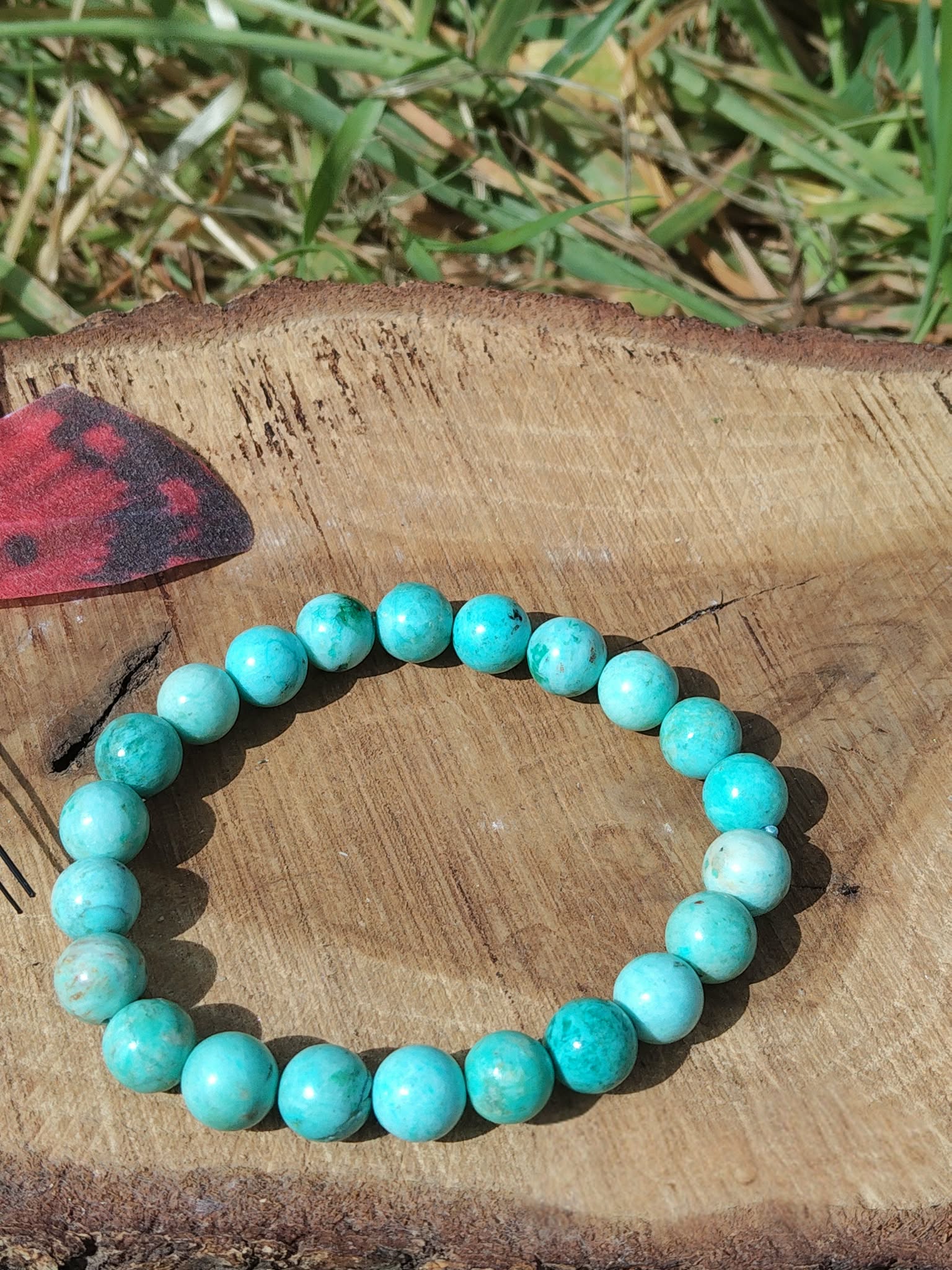 Bracelet turquoise du Pérou sur bois avec herbe en fond, nuances lagon 8 mm pour expression sereine, écoute posée et paix intérieure