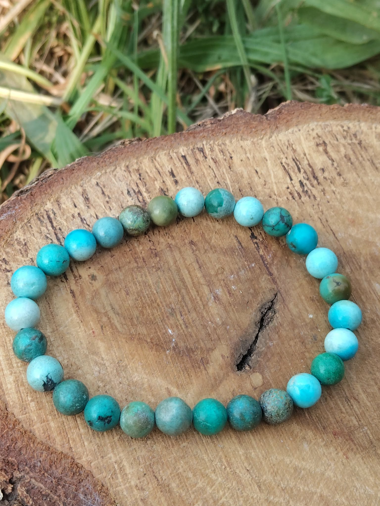 Bracelet turquoise du Tibet sur rondin de bois brut, perles rondes aux tons aqua et vert forêt, recentrage et harmonie intérieure
