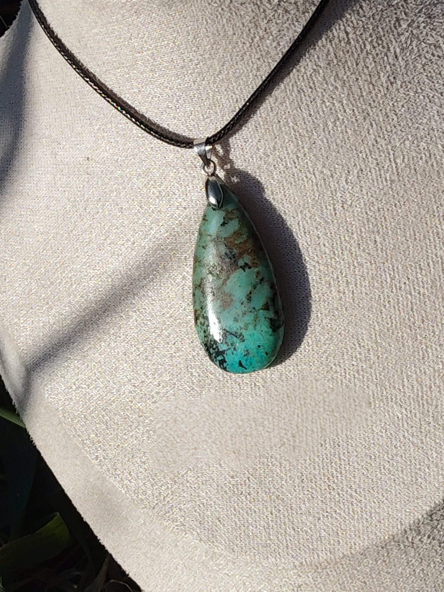 Collier cordon noir avec pendentif turquoise africaine goutte bleu-vert marbrée porté au cou, jaspe africain associé à l’assurance, à la sérénité relationnelle et à l’équilibre affectif.