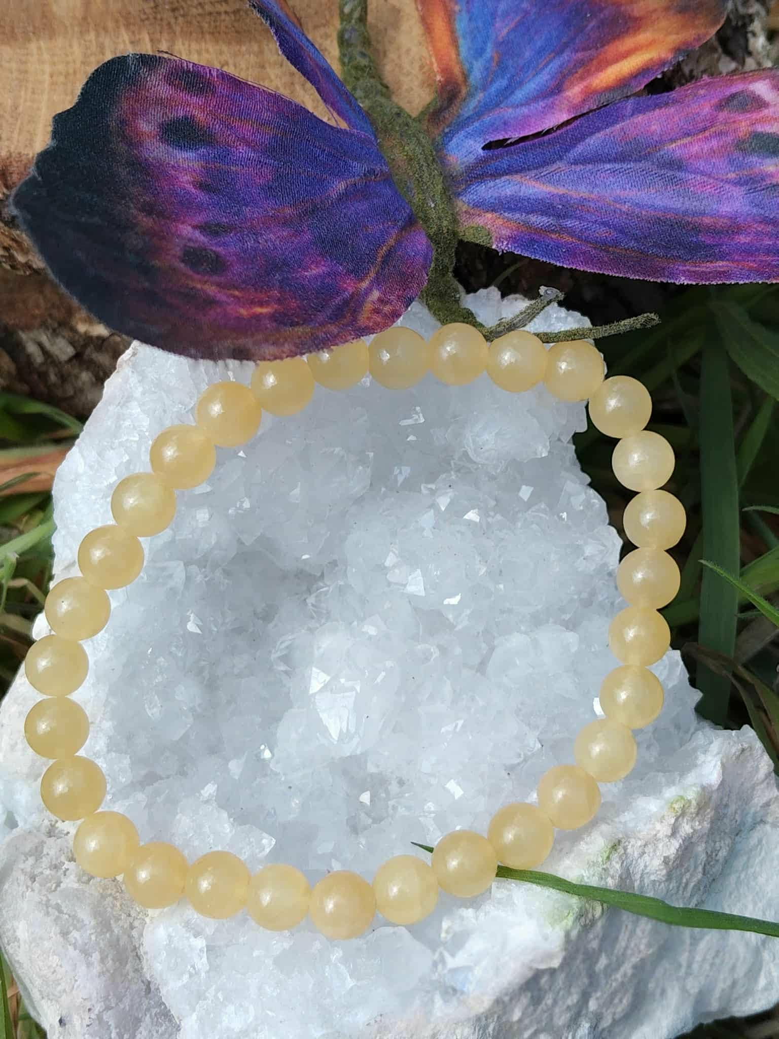 Bracelet calcite jaune posé sur géode claire avec papillon, bijou lumineux pour optimisme, stabilité émotionnelle et attention posée
