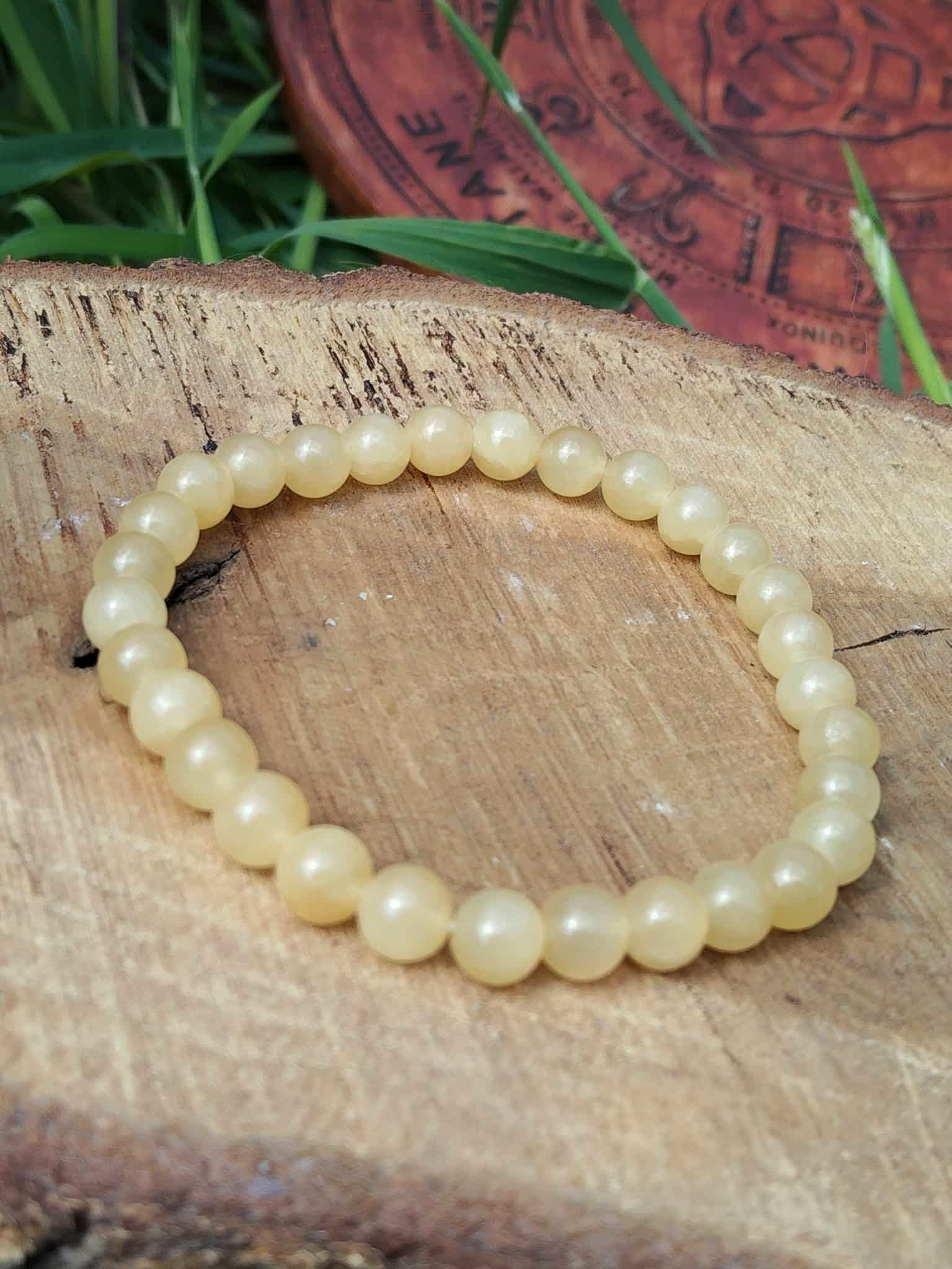 Bracelet en calcite jaune posé sur bois brut avec brins verts, bijou en pierre naturelle pour bonne humeur, élan positif et esprit plus clair