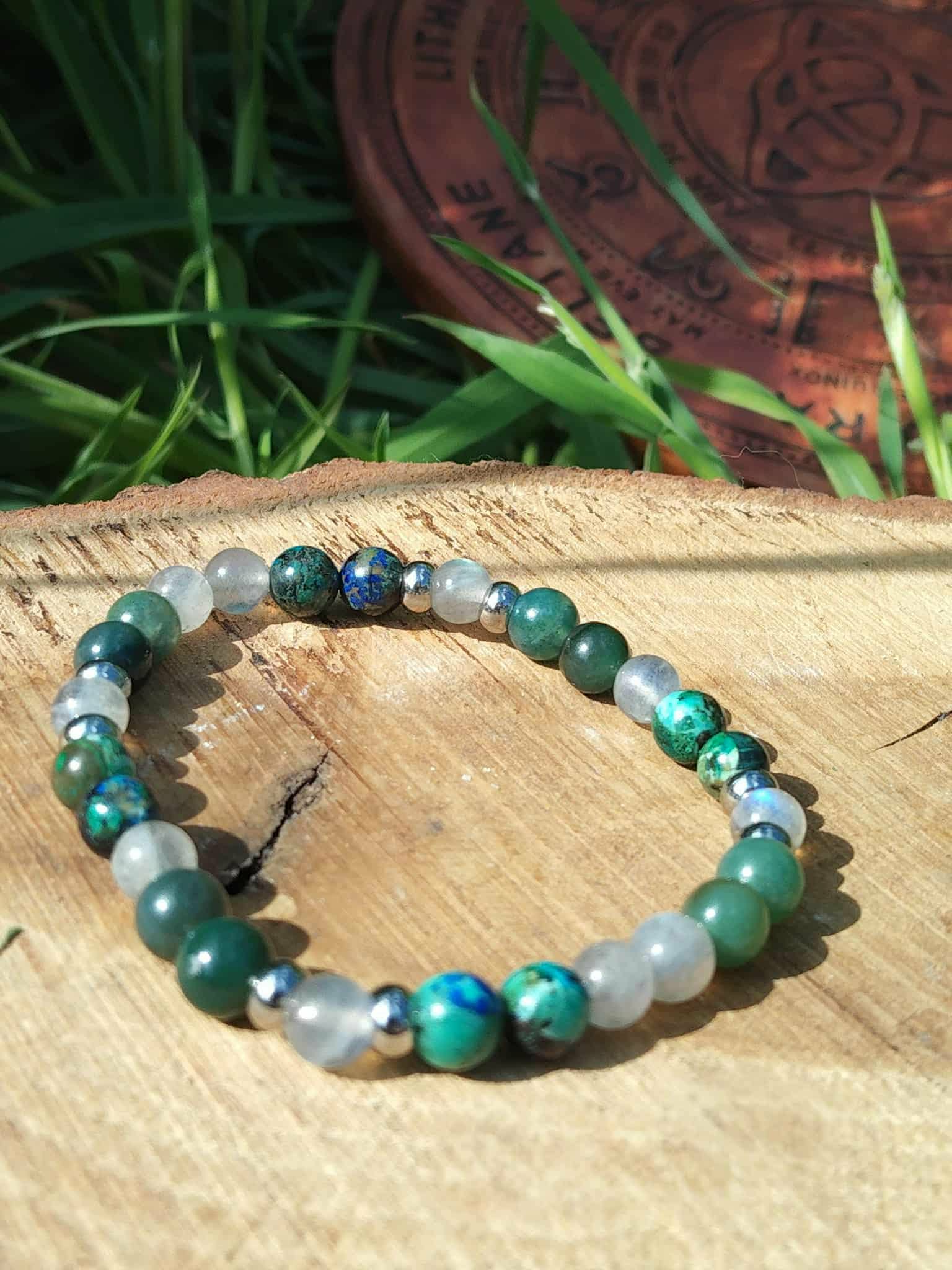 Bracelet Éveil spirituel photographié sur planche de bois avec herbes vertes et décor gravé, lucidité, enracinement et paix du mental
