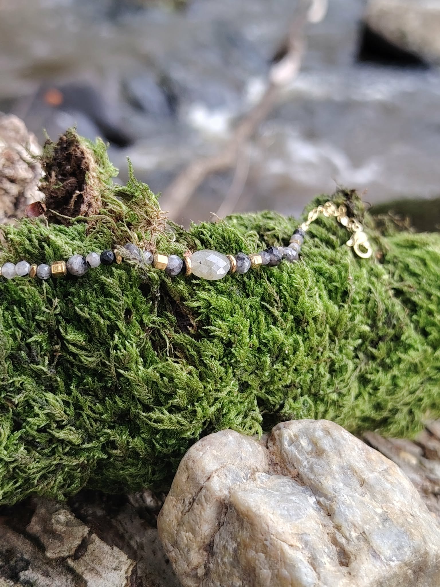 Bracelet labradorite avec fermoir visible sur mousse verte et galets, finitions dorées, maîtrise émotionnelle et confiance tranquille.