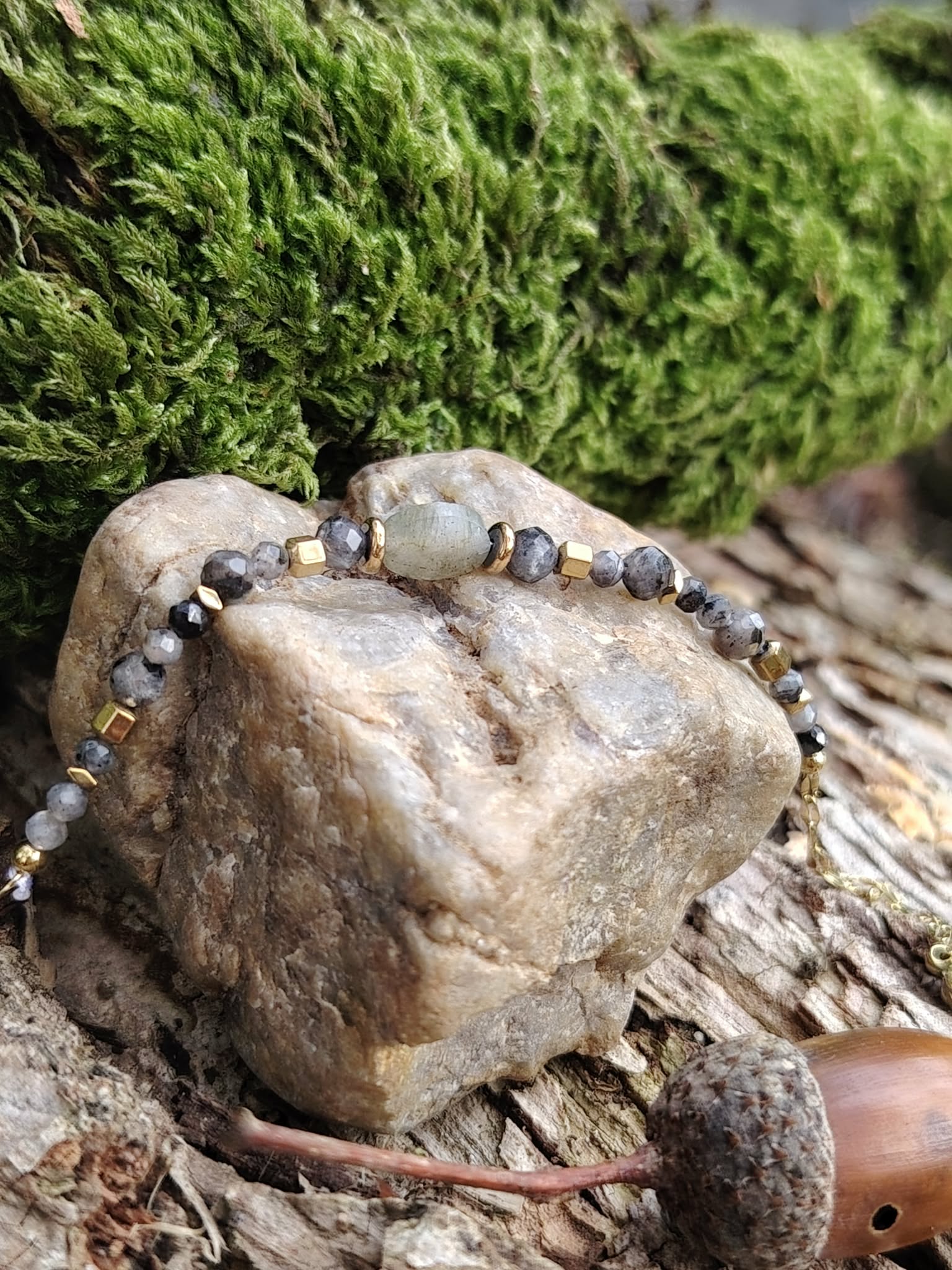 Bracelet labradorite facettée posé sur gros galet avec mousse verte et bois, respiration mentale et solidité intérieure